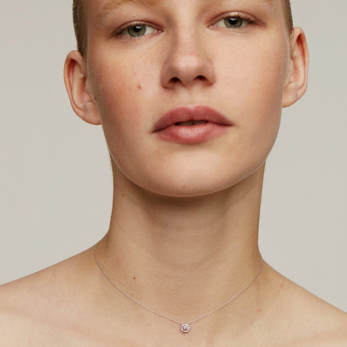 Colgante de oro blanco de 18K con diamante de 0,11cts y orla de diamantes