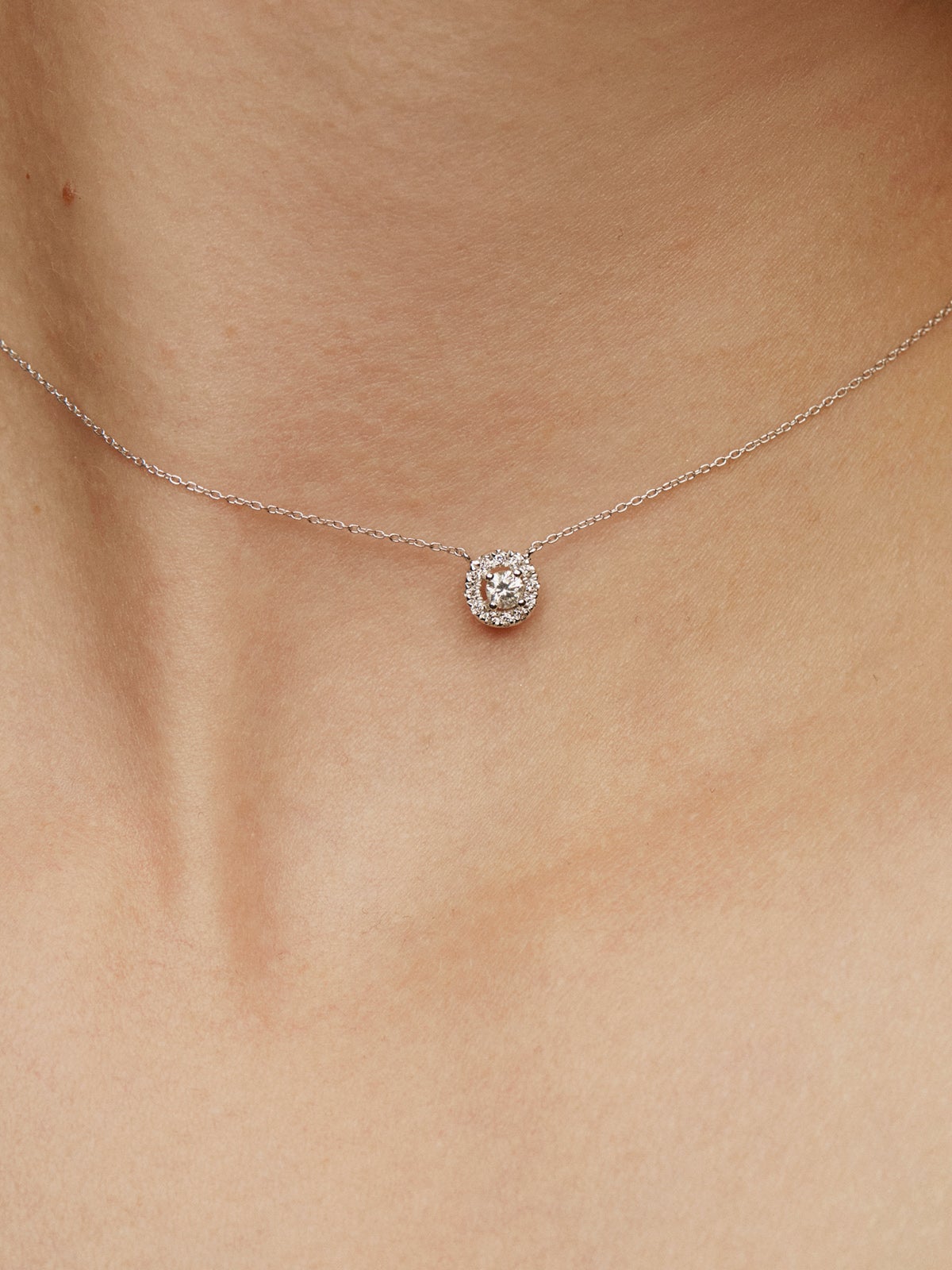 Colgante de oro blanco de 18K con diamante de 0,11cts y orla de diamantes
