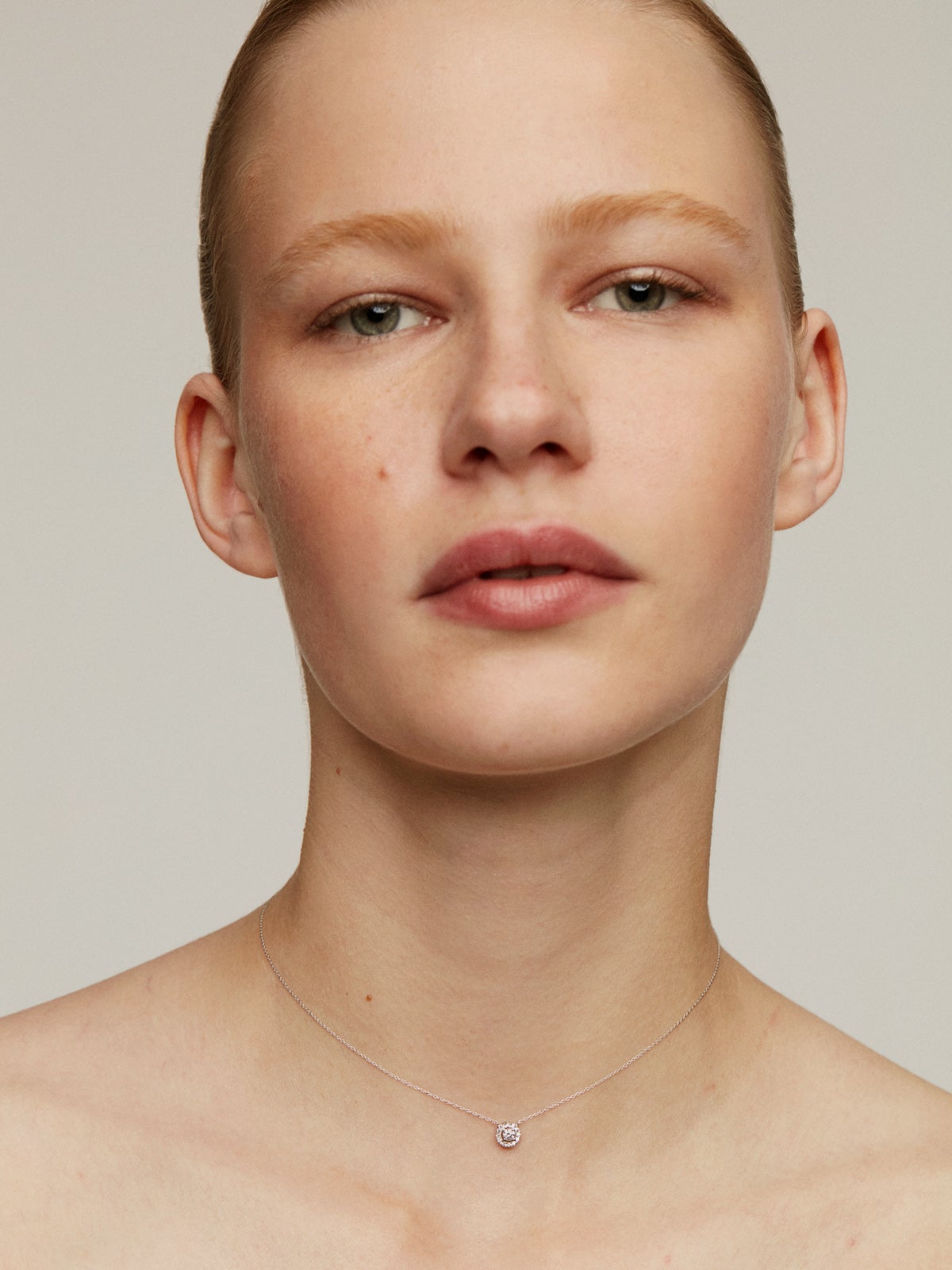 Colgante de oro blanco de 18K con diamante de 0,11cts y orla de diamantes