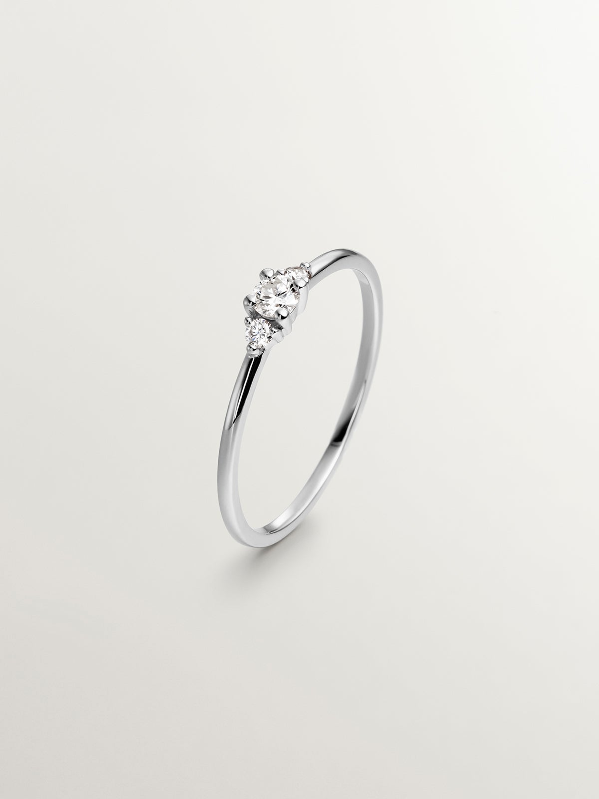 Anillo tresillo de oro blanco de 18K con diamante central de 0,10cts y diamantes