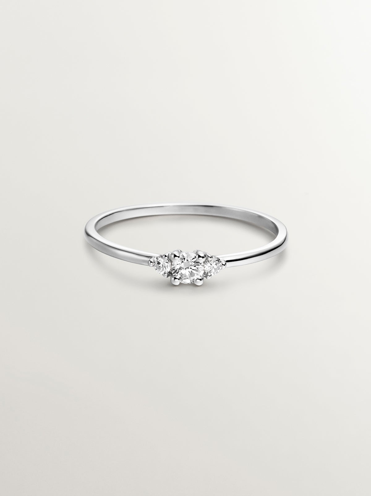 Anillo tresillo de oro blanco de 18K con diamante central de 0,10cts y diamantes