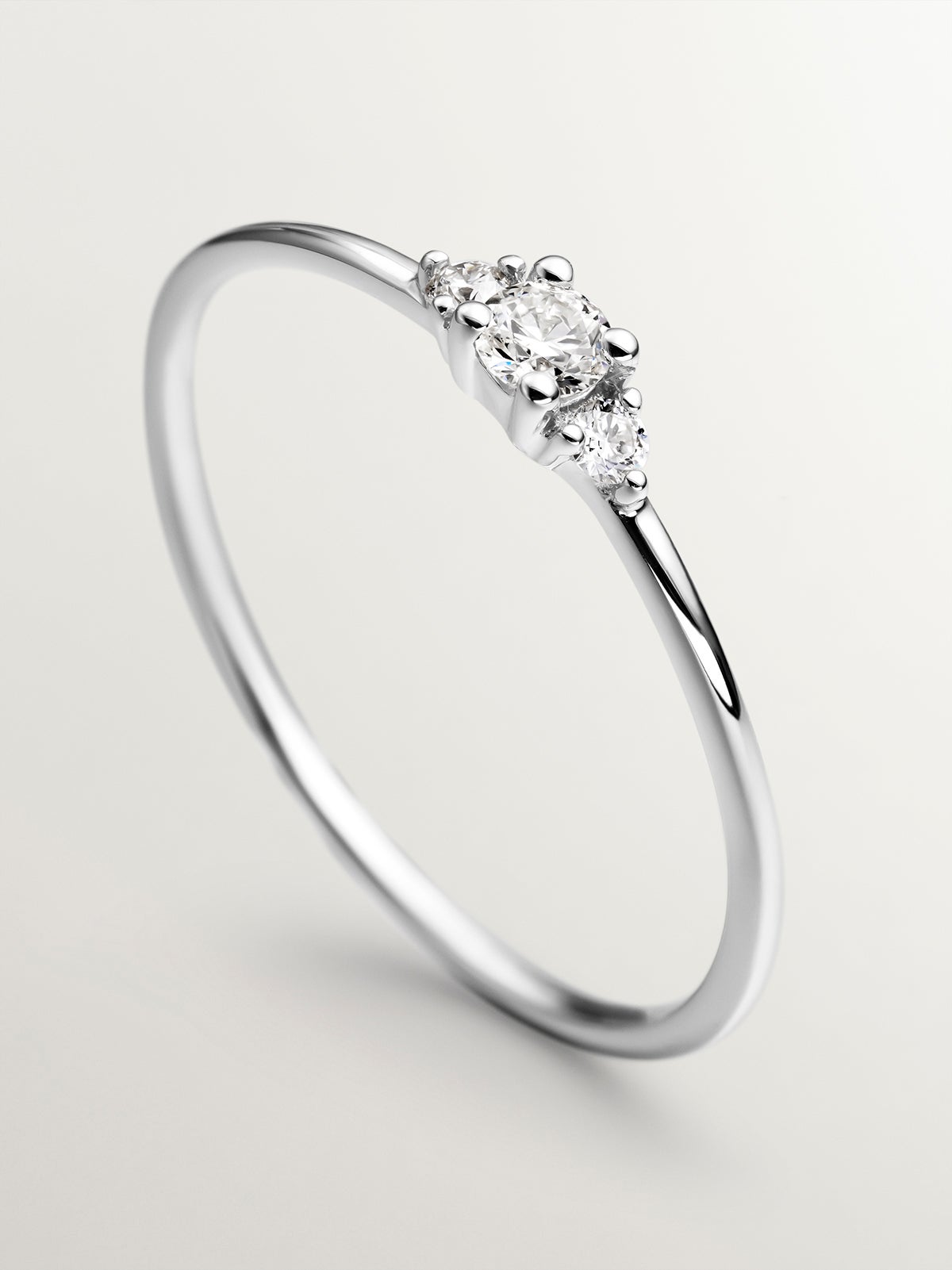 Anillo tresillo de oro blanco de 18K con diamante central de 0,10cts y diamantes