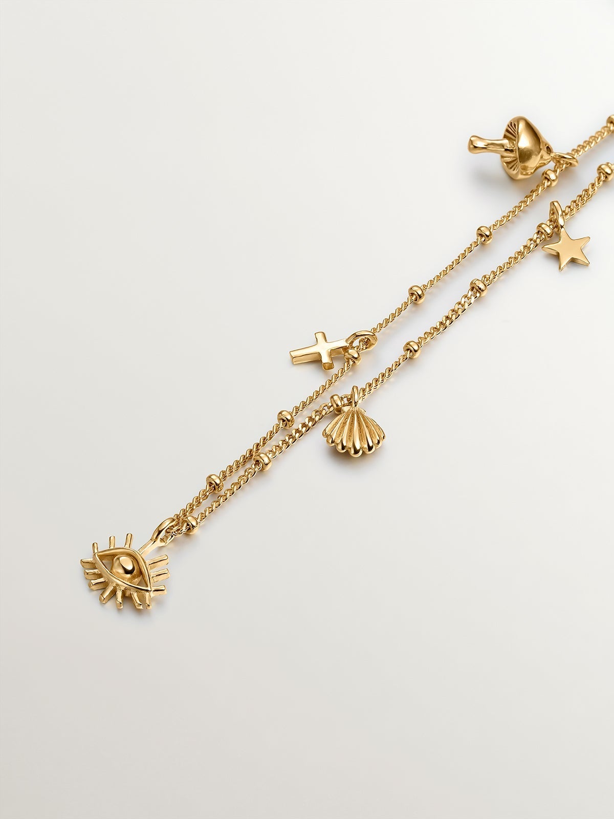 Pulsera de plata 925 bañada en oro amarillo de 18K con motivos de seta, cruz, ojo, concha y estrella