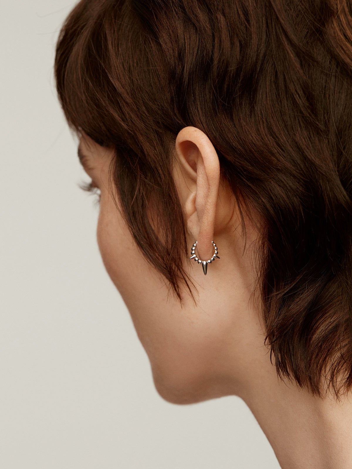 Pendiente individual de oro blanco de 9K con bolitas y pinchos