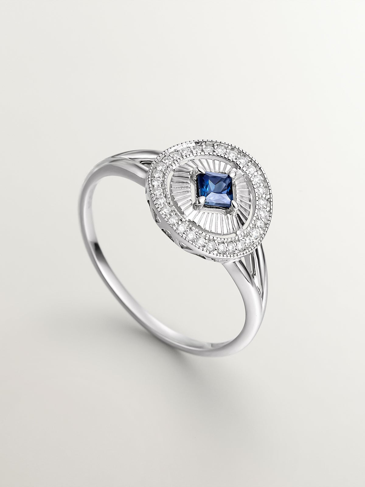 Anillo de oro blanco de 18K con diamantes en talla brillante y zafiro azul en talla princesa