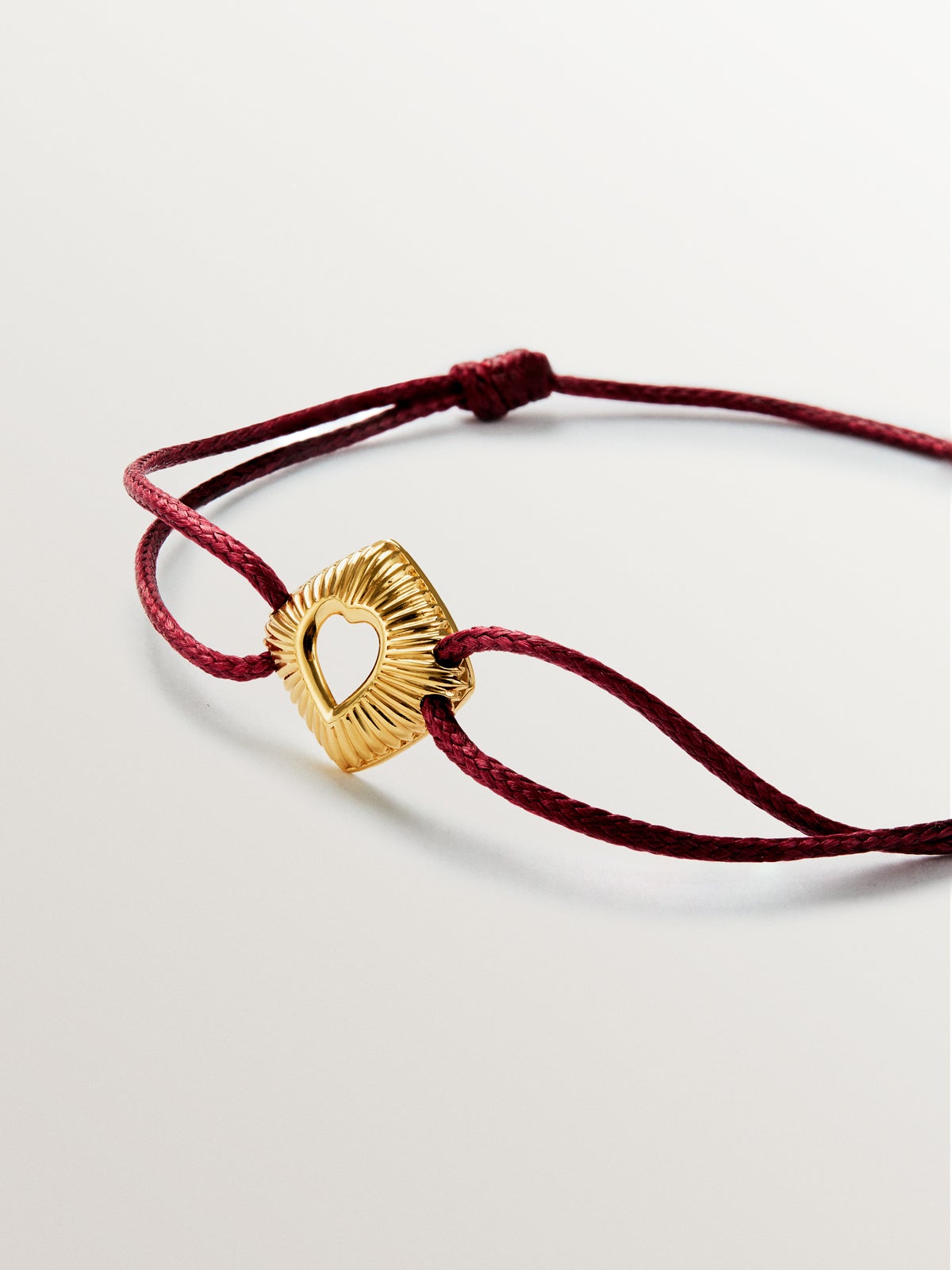 Pulsera de plata 925 bañada en oro amarillo de 18K con forma de corazón en textura de guilloché y con cuerda roja