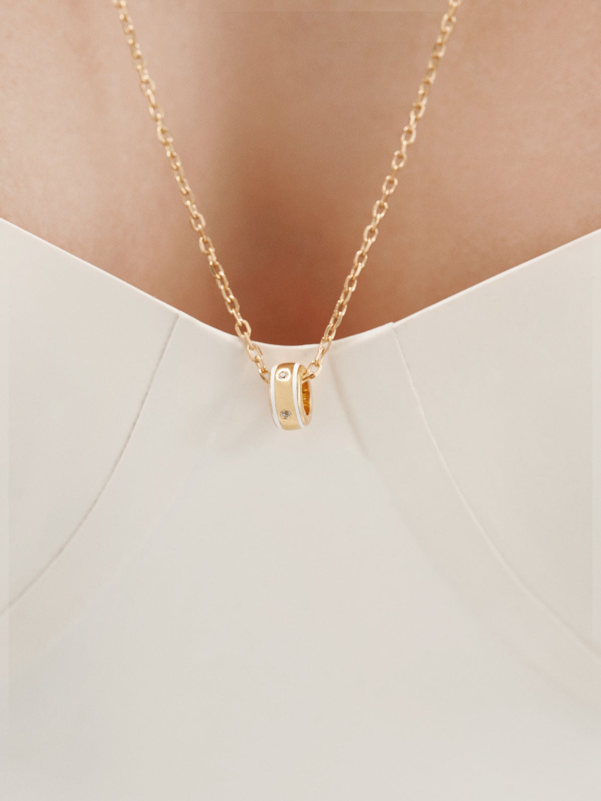 Charm de plata 925 bañada en oro amarillo de 18K con topacios blancos y esmalte blanco con forma circular