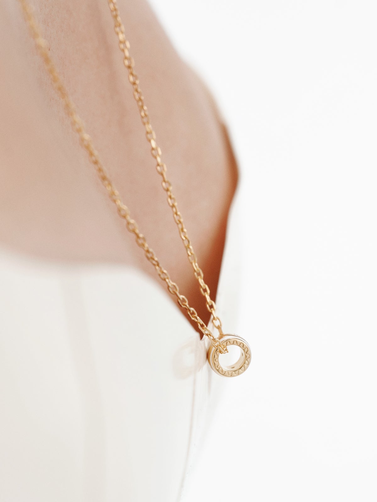 Charm de plata 925 bañada en oro amarillo de 18K con topacios blancos y esmalte blanco con forma circular