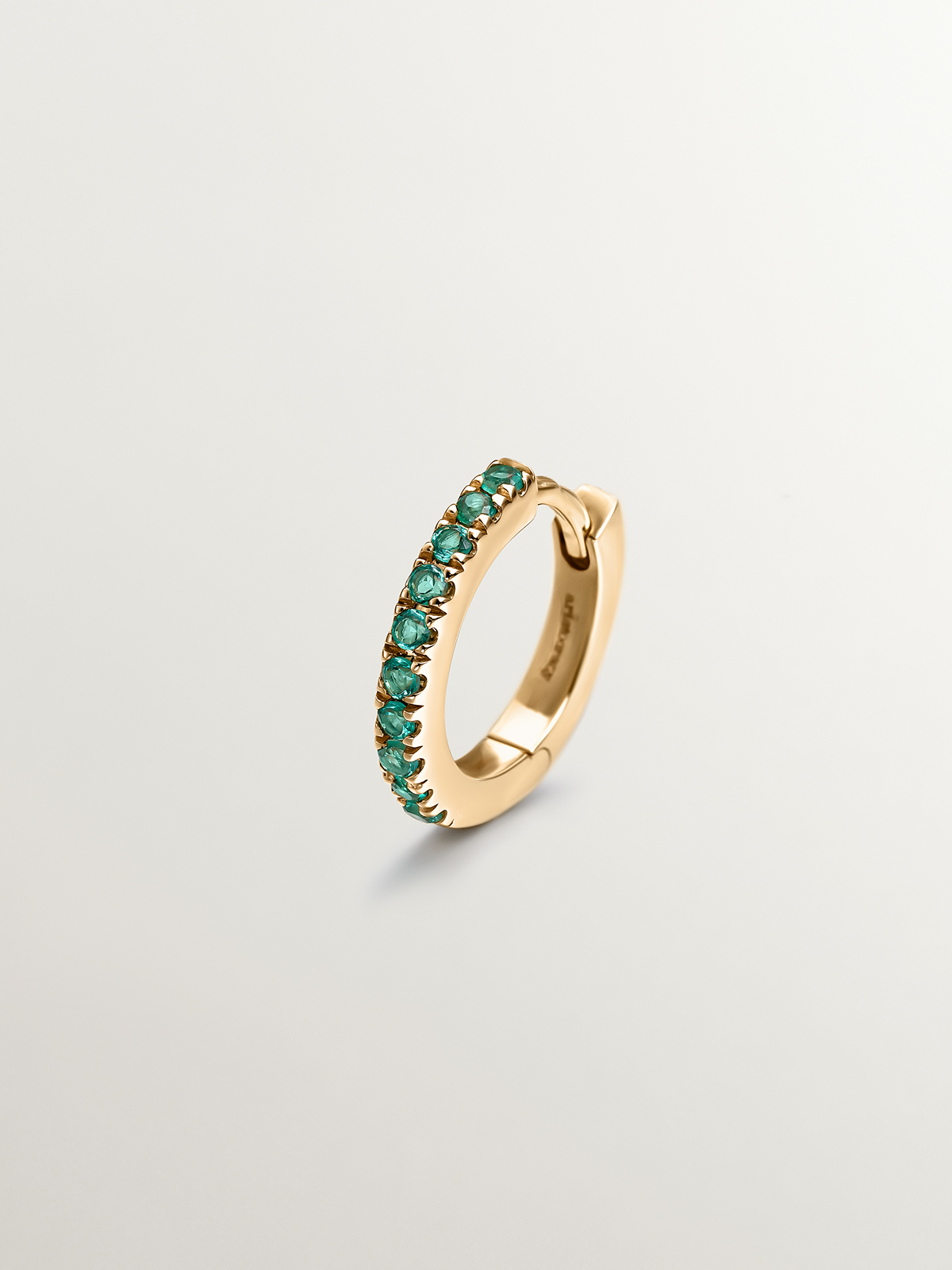 Small individual 9k yellow gold hoop earring with emeralds.