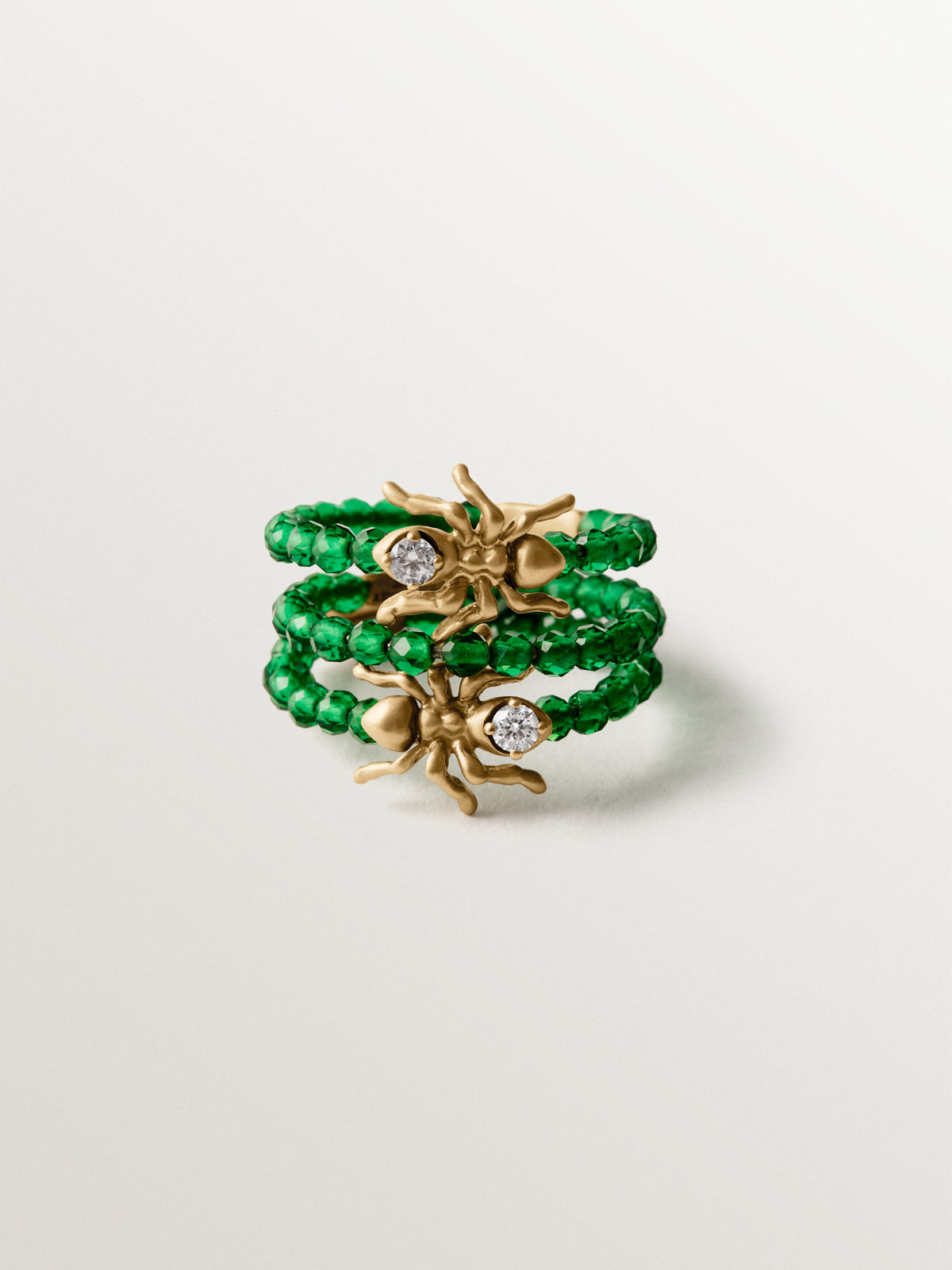 Anillo triple bañado en oro amarillo con cristales blancos y verdes y motivos de hormigas