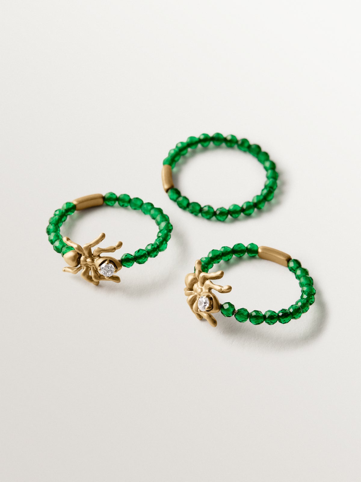 Anillo triple bañado en oro amarillo con cristales blancos y verdes y motivos de hormigas