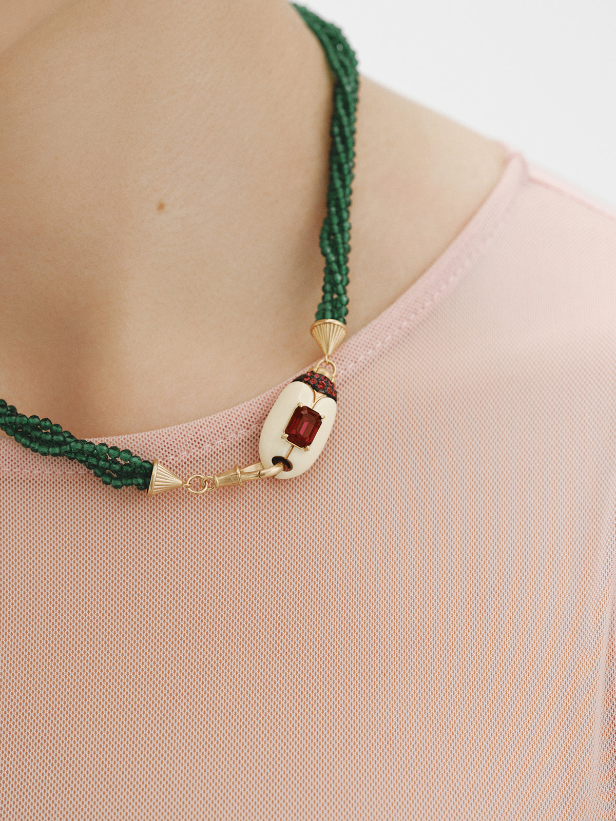 Collar bañado en oro amarillo con cuentas de cristales verdes y forma de escarabajo con cristales rojos