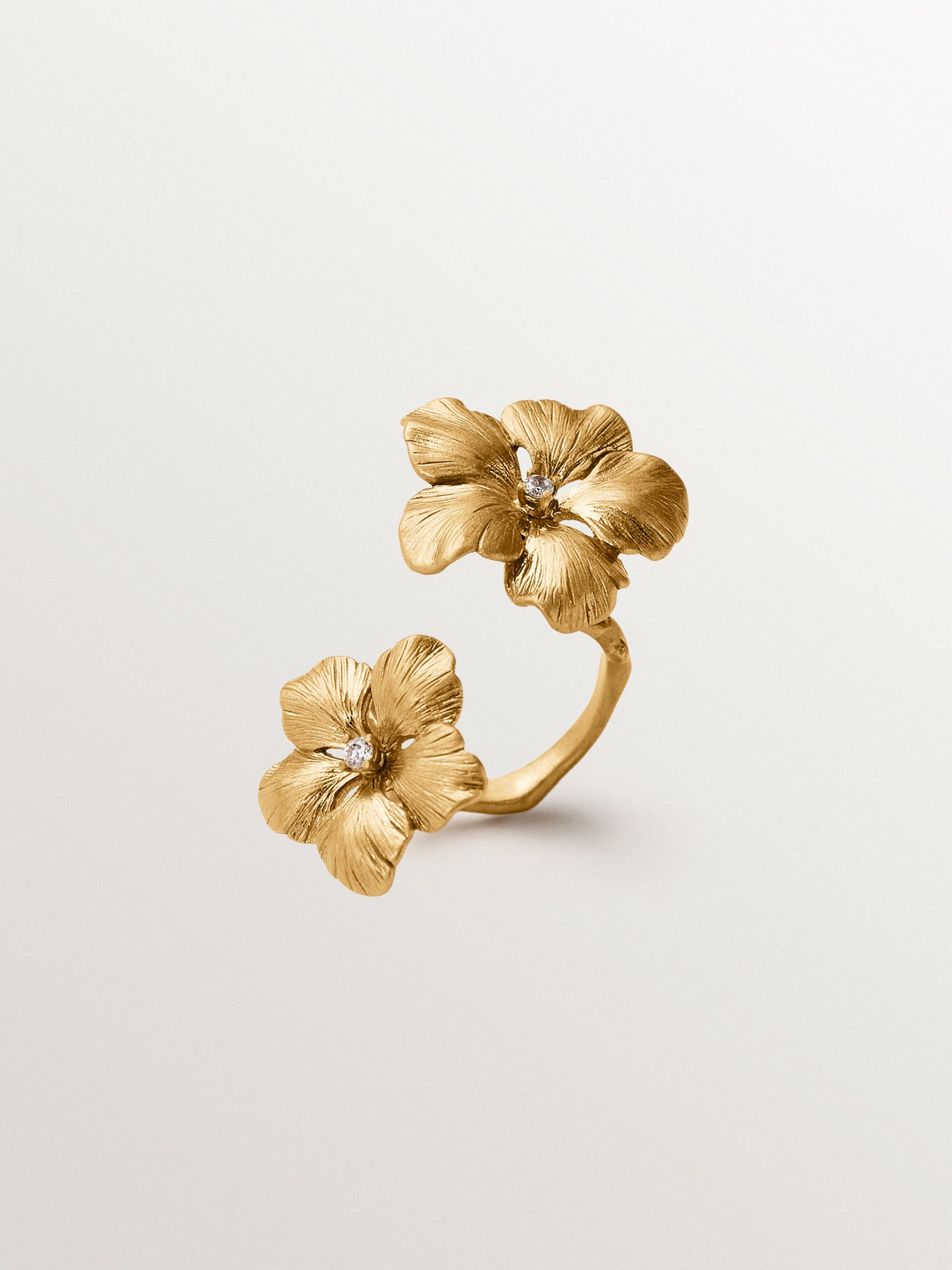 Anillo abierto bañado en oro amarillo con cristales y motivo de flor