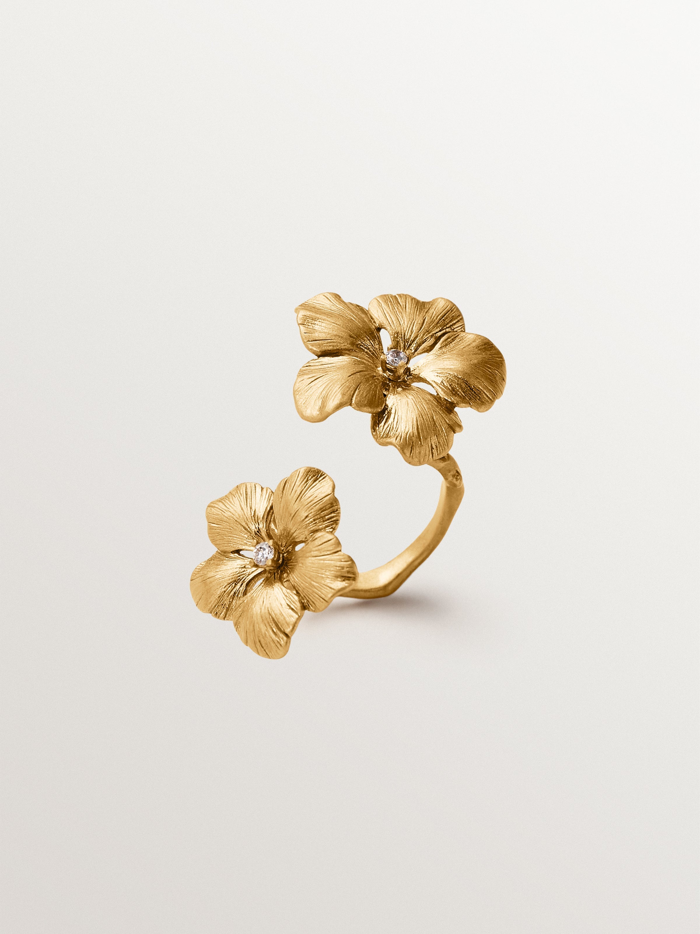 Anillo abierto bañado en oro amarillo con cristales y motivo de flor