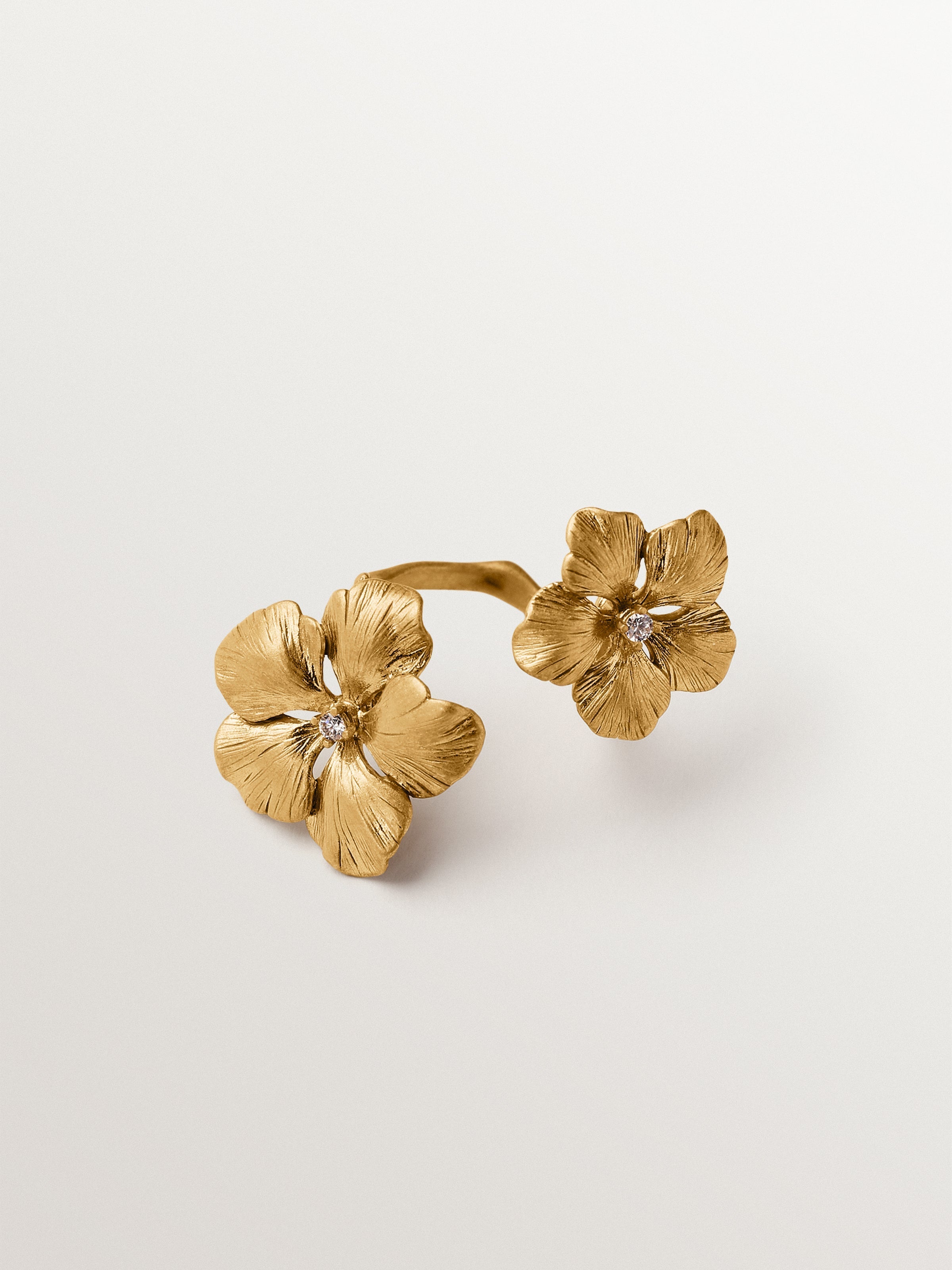 Anillo abierto bañado en oro amarillo con cristales y motivo de flor