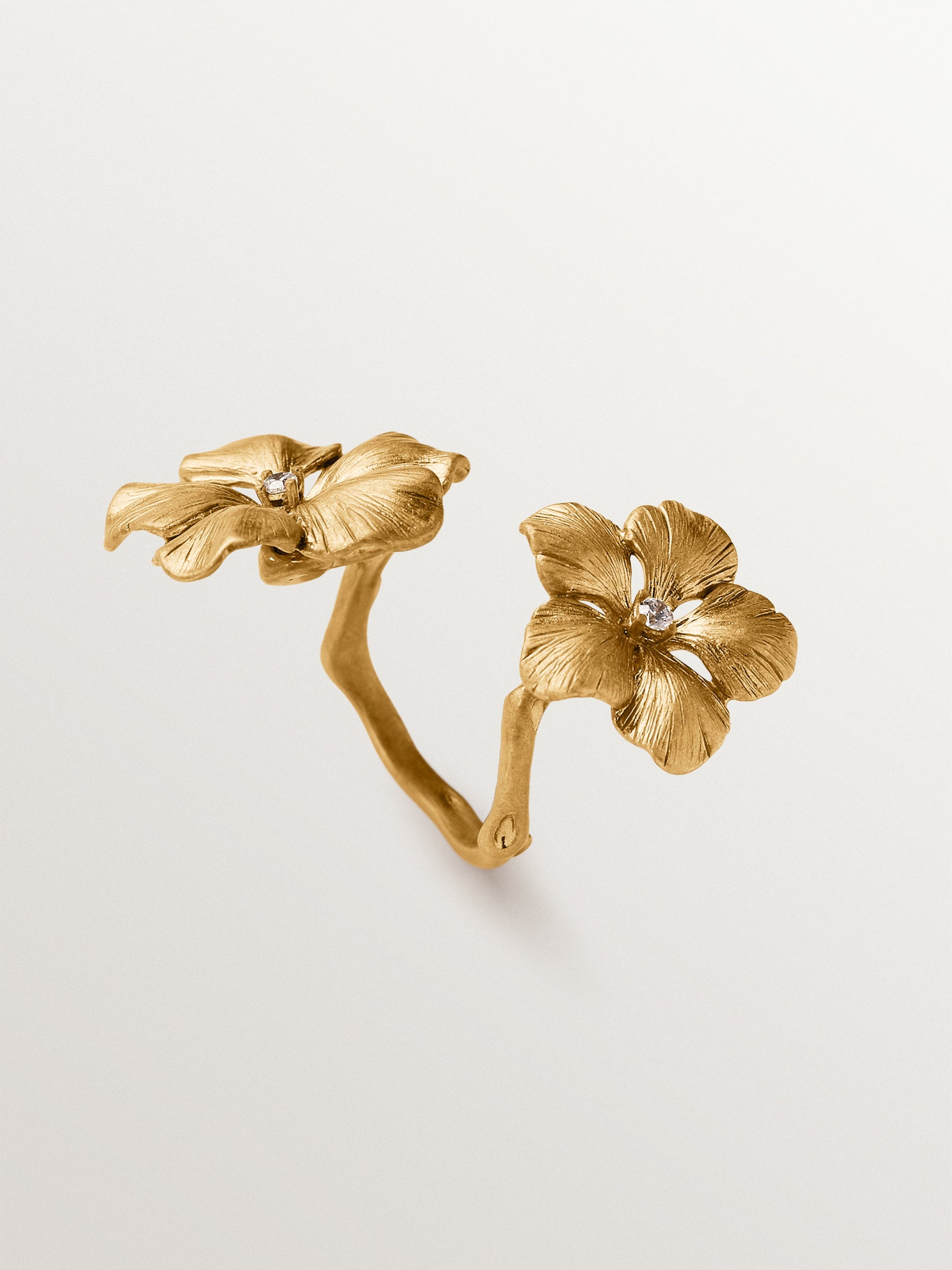 Anillo abierto bañado en oro amarillo con cristales y motivo de flor