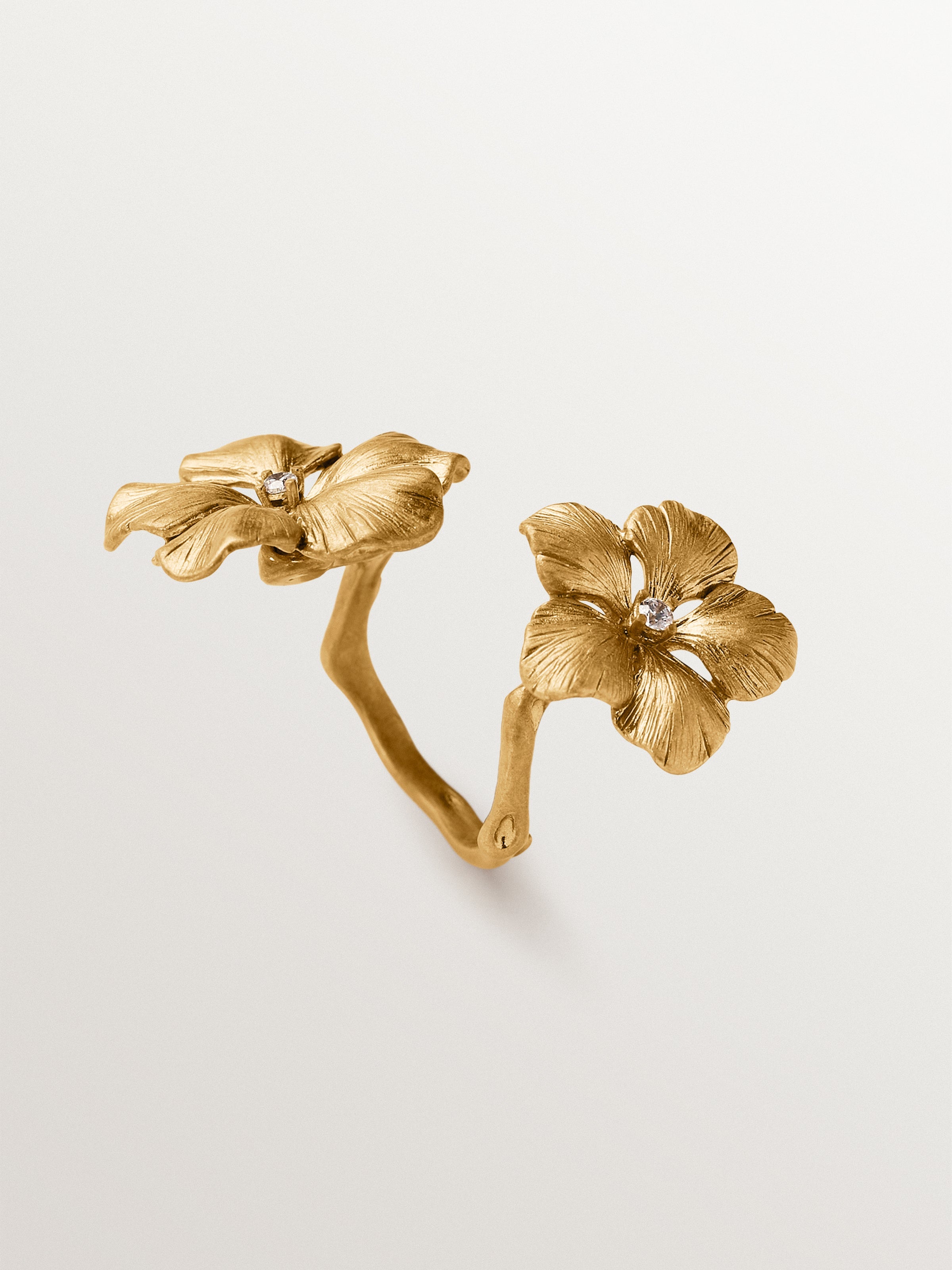 Anillo abierto bañado en oro amarillo con cristales y motivo de flor