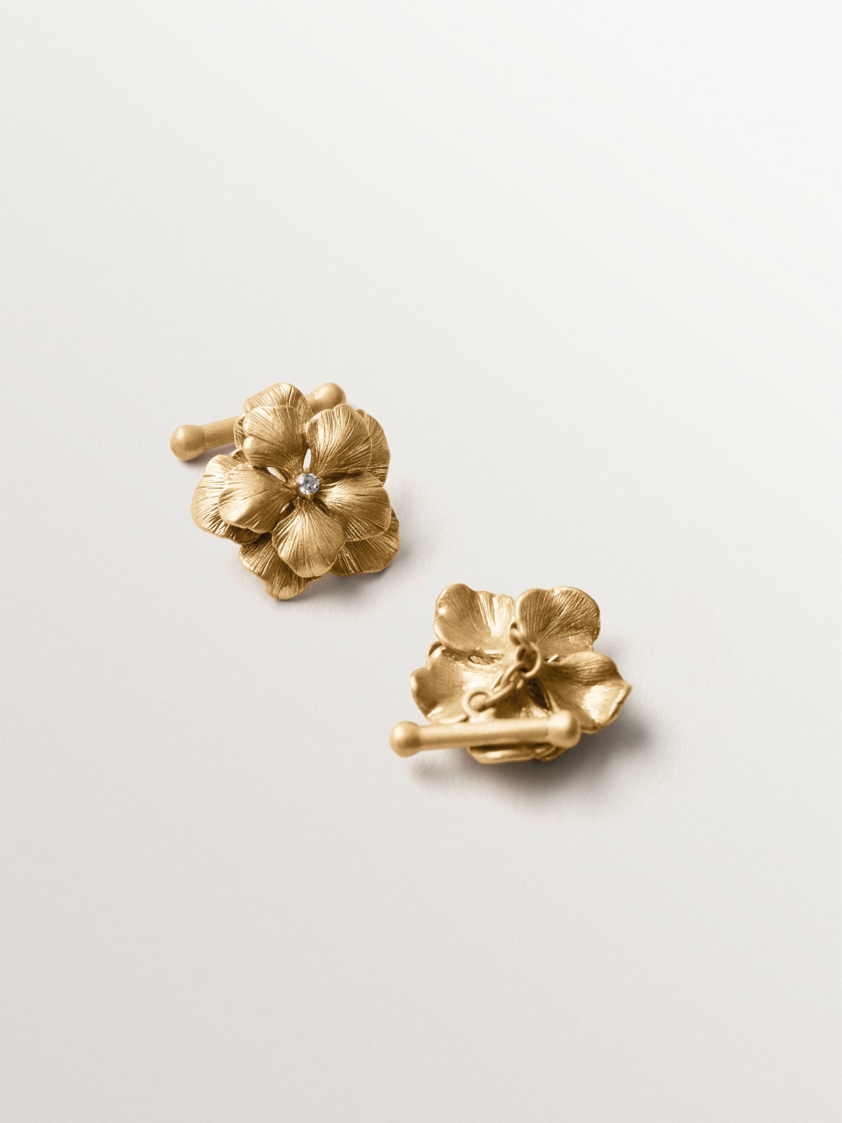 Gemelos bañados en oro amarillo con cristales y forma de flor