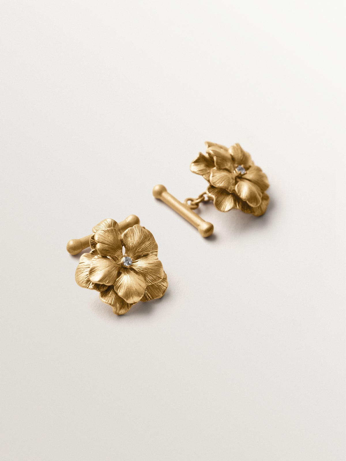 Gemelos bañados en oro amarillo con cristales y forma de flor