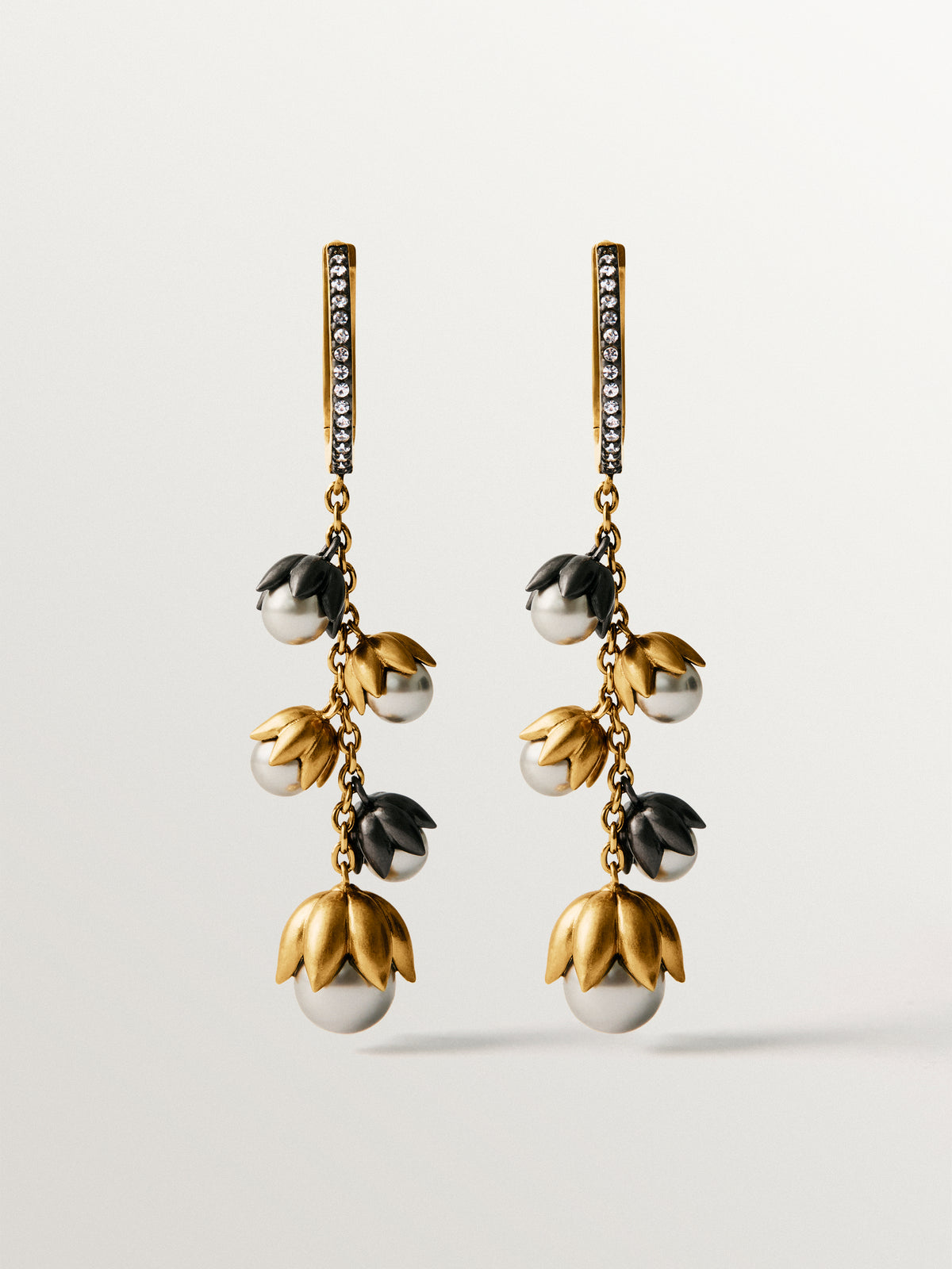 Pendientes bicolor bañados en oro amarillo con acabado gunmetal, cristale blancos y cristales grises en forma de flor