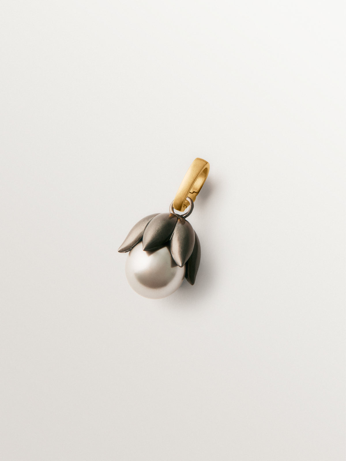 Charm bicolor bañado en oro amarillo con acabado gumetal, perla gris y forma de flor
