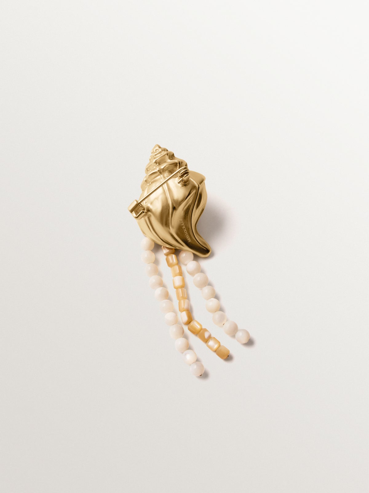 Broche bañado en oro amarillo con cristales, bolitas blancas y forma de concha
