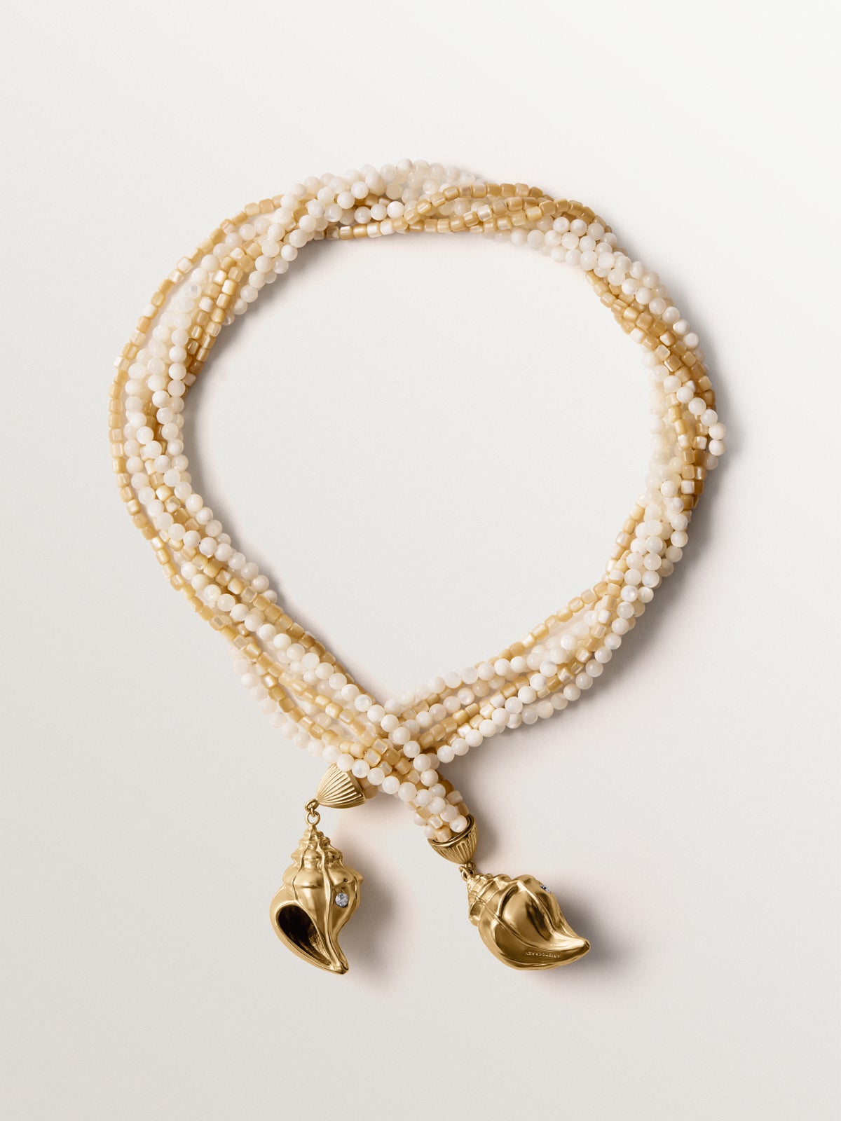 Collar bañado en oro amarillo con cristales, bolitas blancas y forma de concha