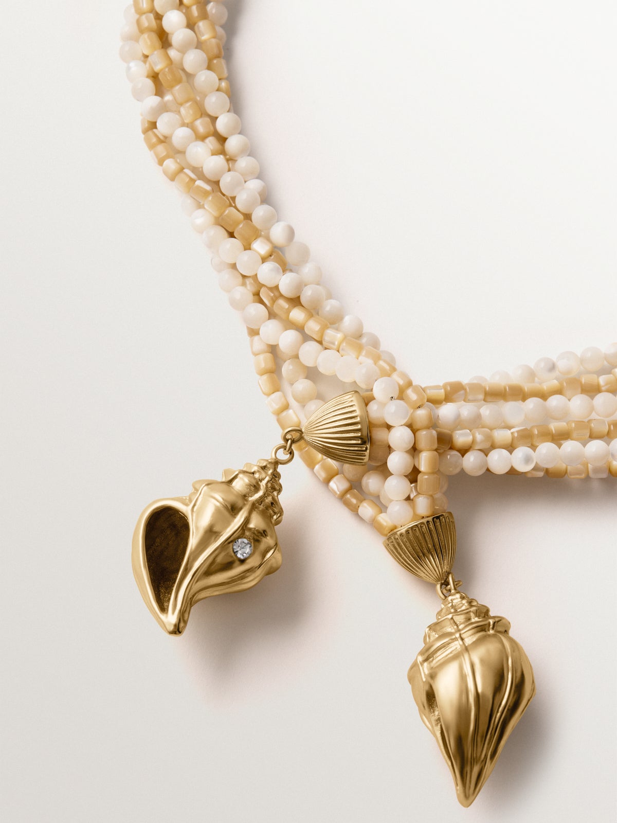 Collar bañado en oro amarillo con cristales, bolitas blancas y forma de concha