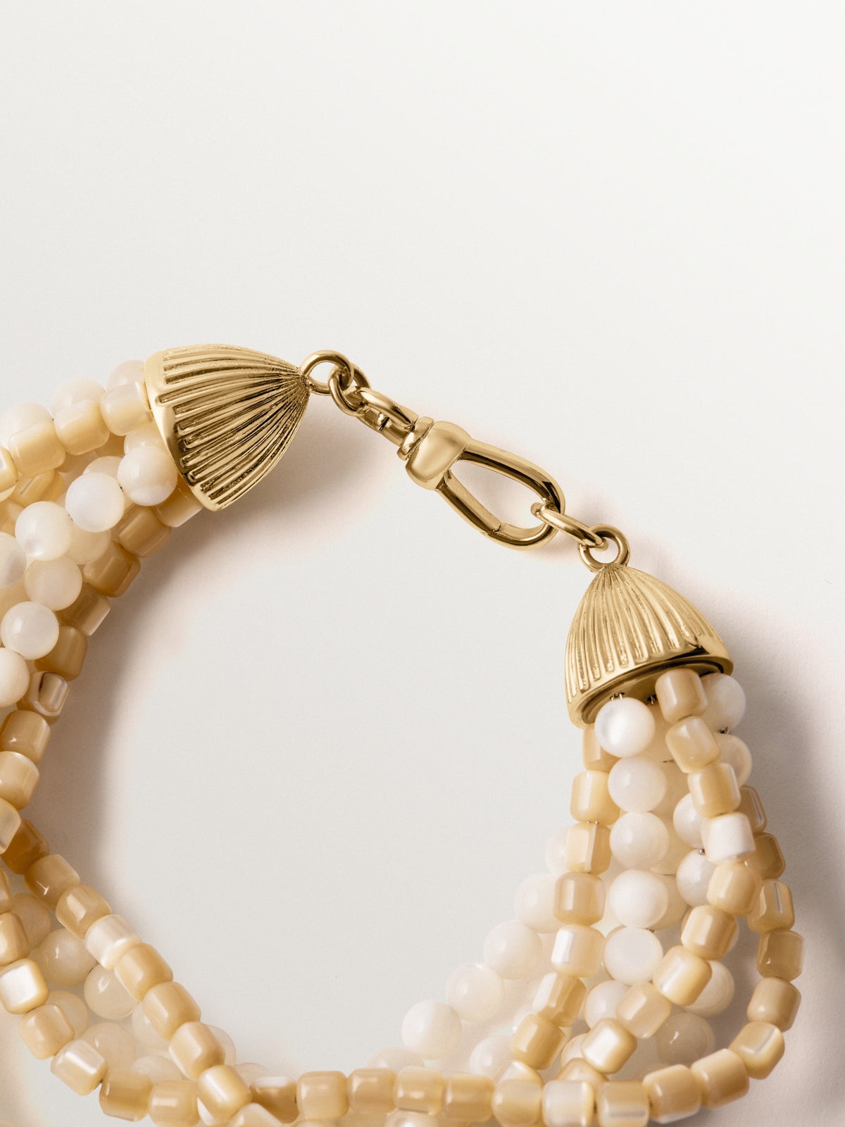 Pulsera bañada en oro amarillo con bolitas blancas y crema