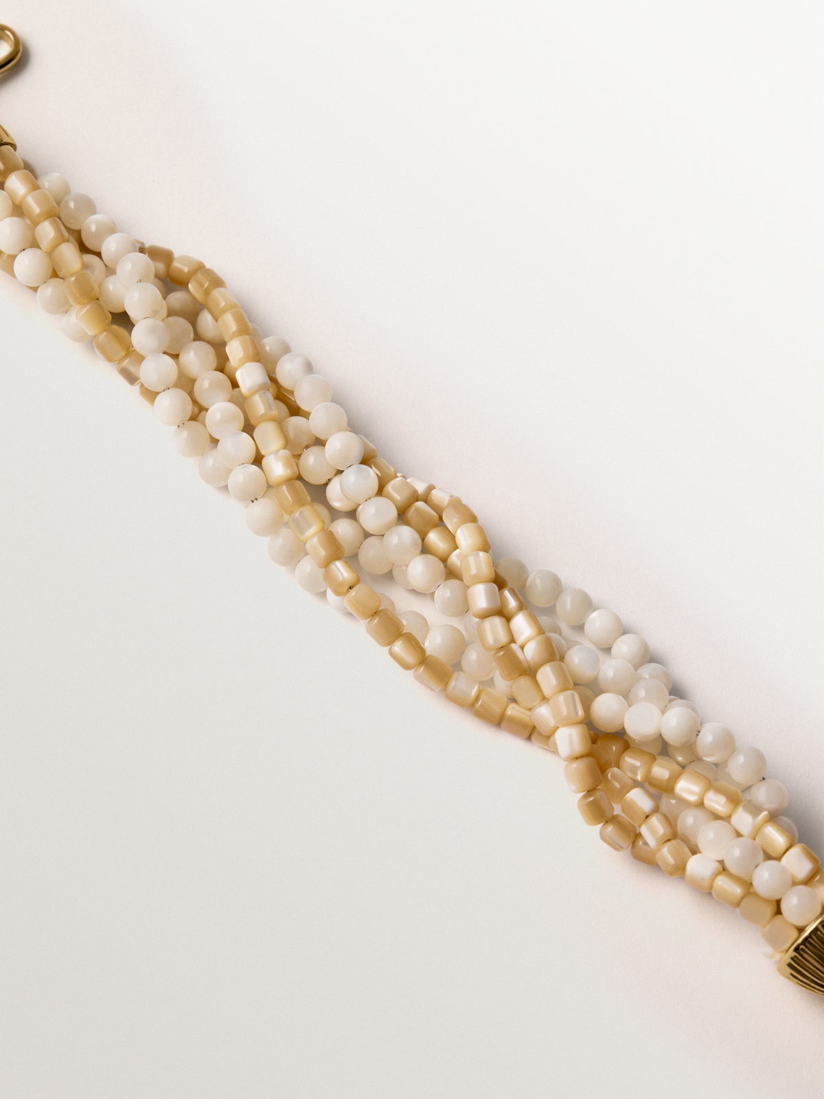 Pulsera bañada en oro amarillo con bolitas blancas y crema