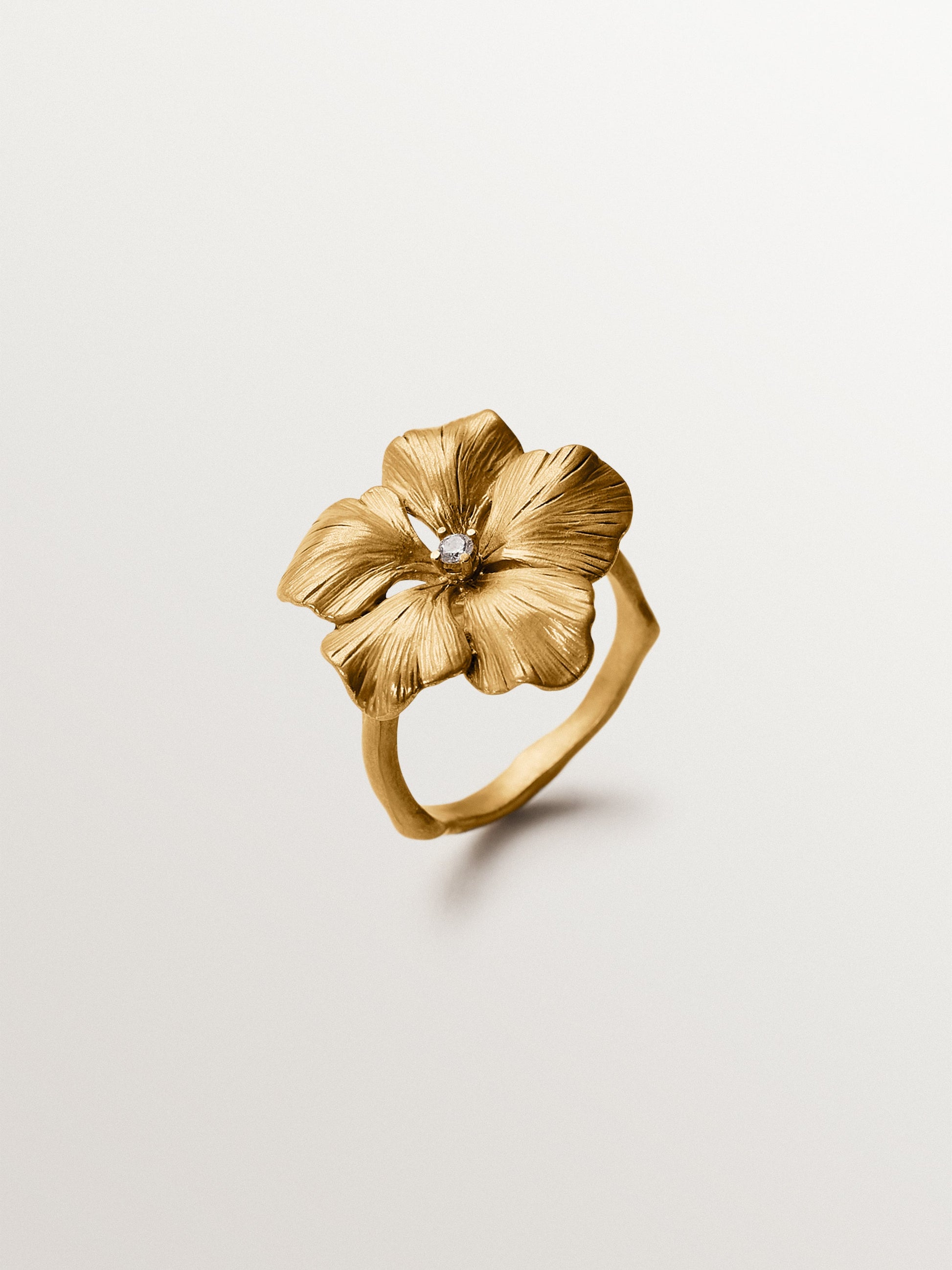 Anillo bañado en oro amarillo con cristal y forma de flor