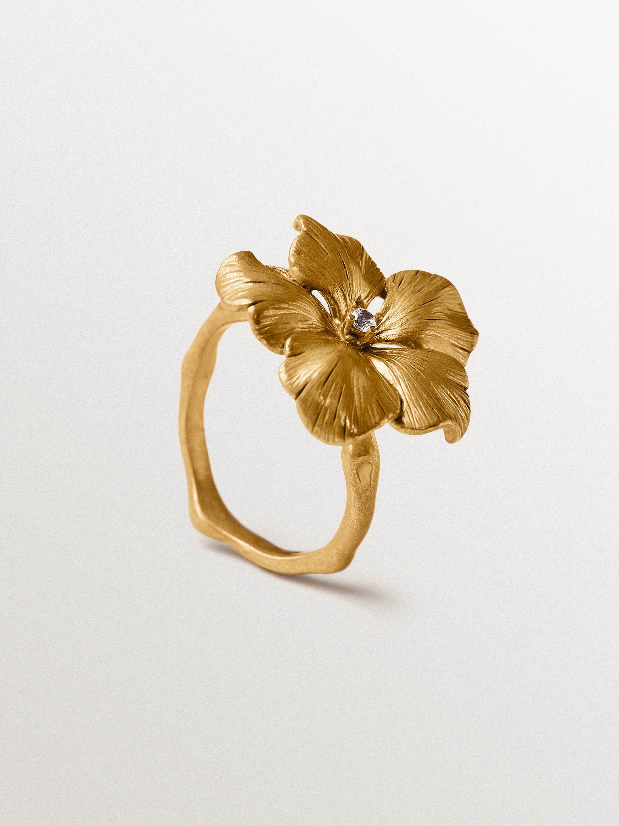 Anillo bañado en oro amarillo con cristal y forma de flor