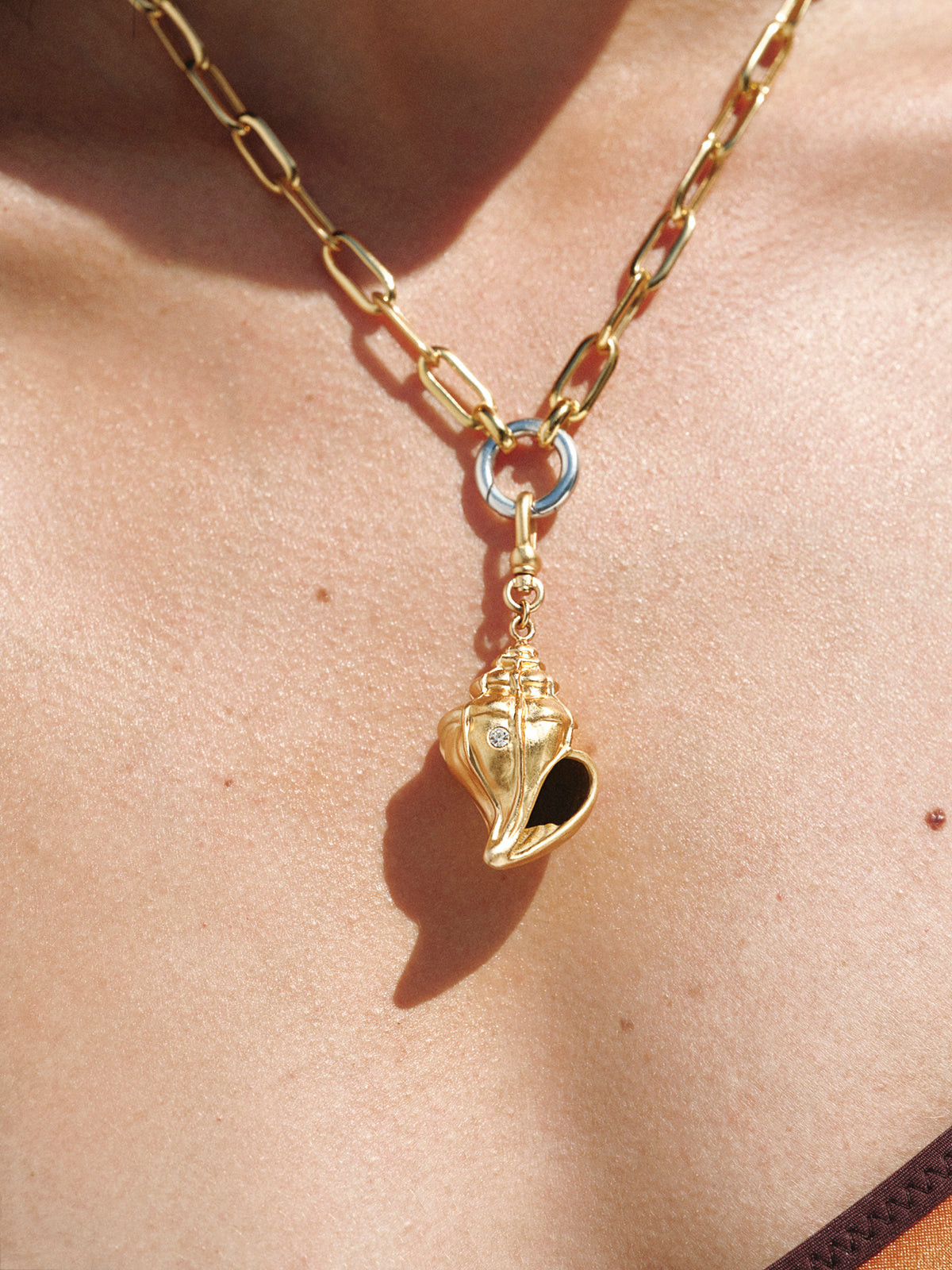 Charm bañado en oro amarillo con cristales y forma de concha 