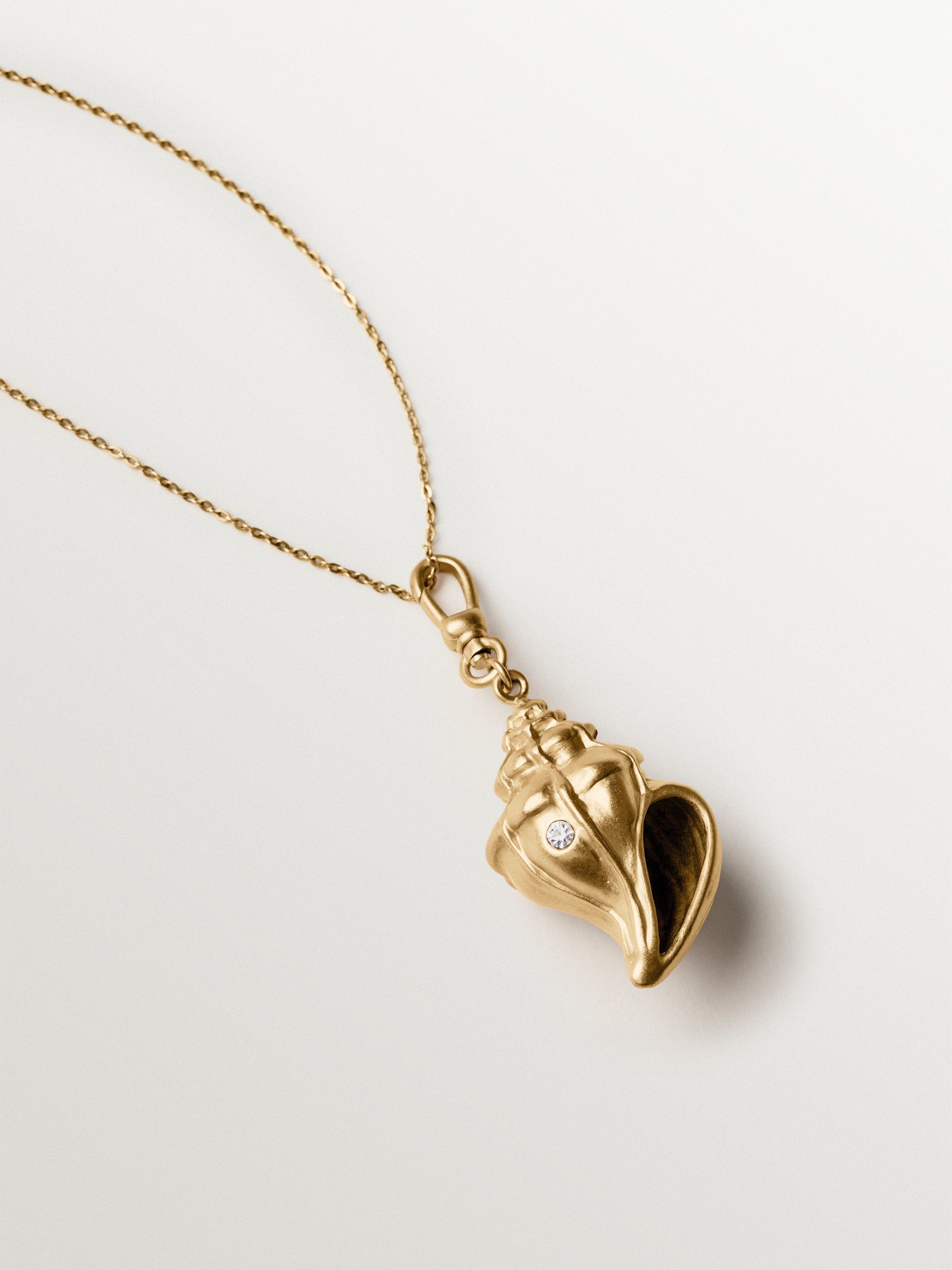 Charm bañado en oro amarillo con cristales y forma de concha
