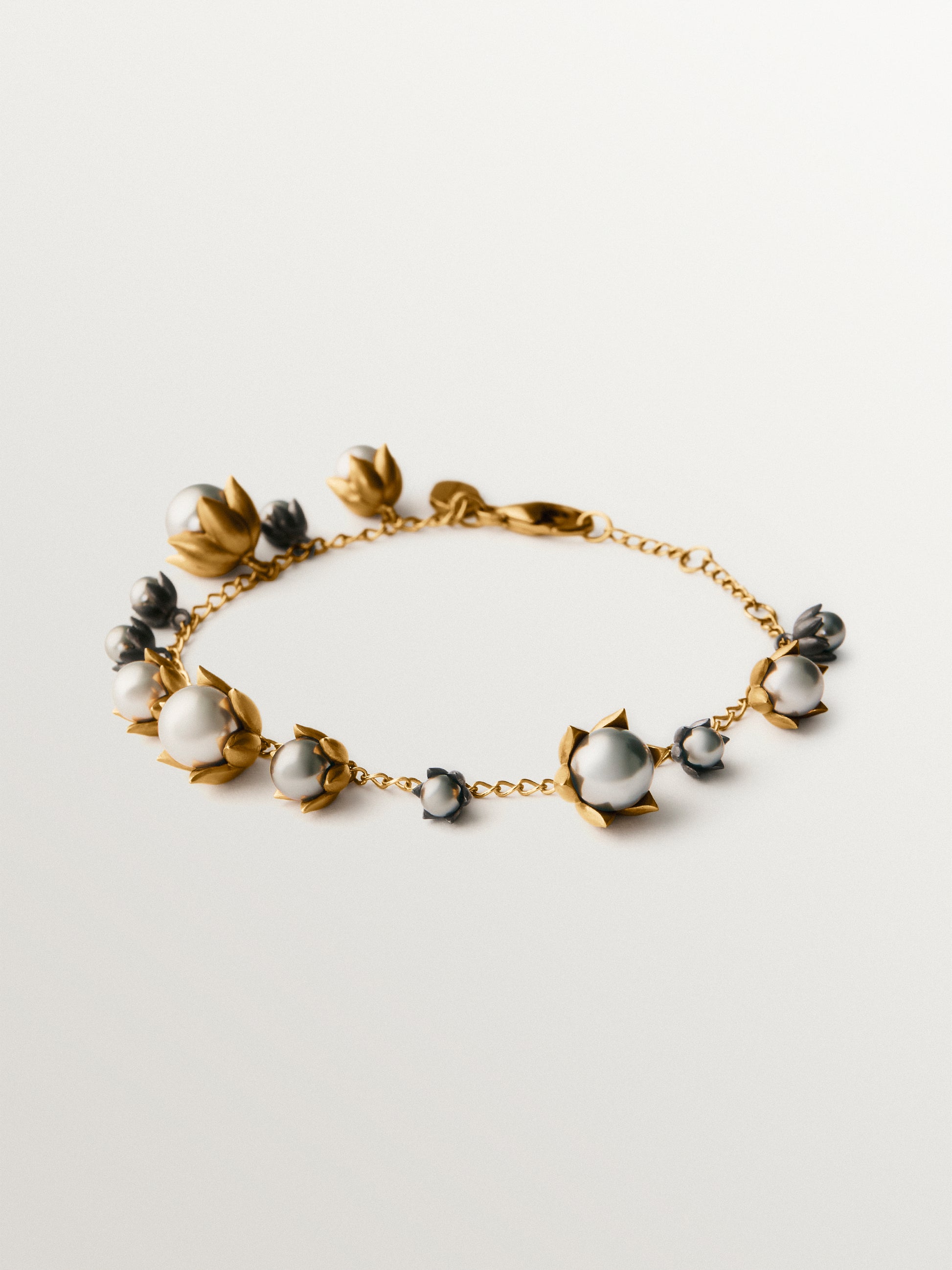 Pulsera bicolor bañada en oro amarillo y acabado gunmetal con perlas grises y motivos florales