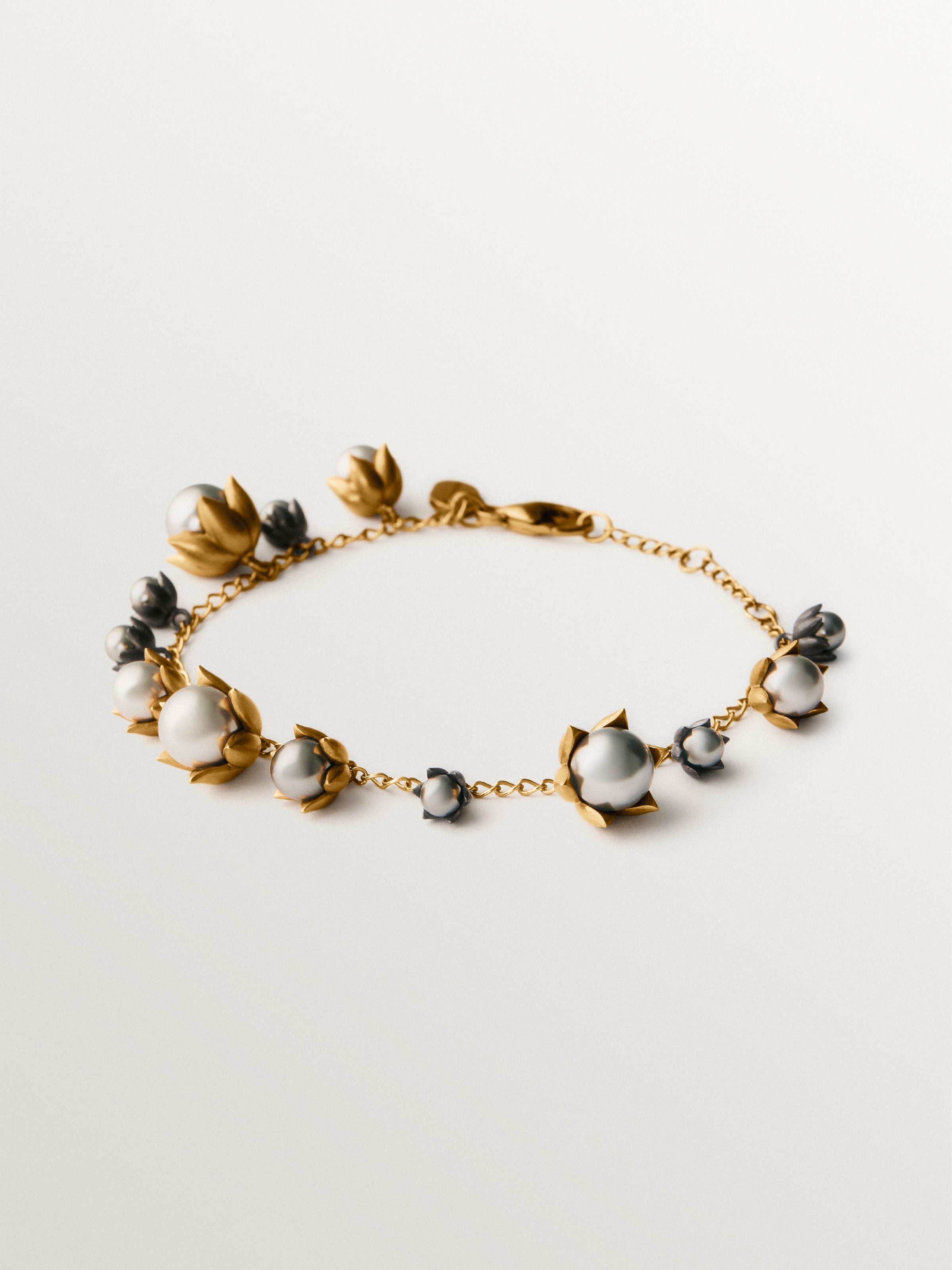 Pulsera bicolor bañada en oro amarillo y acabado gunmetal con perlas grises y motivos florales