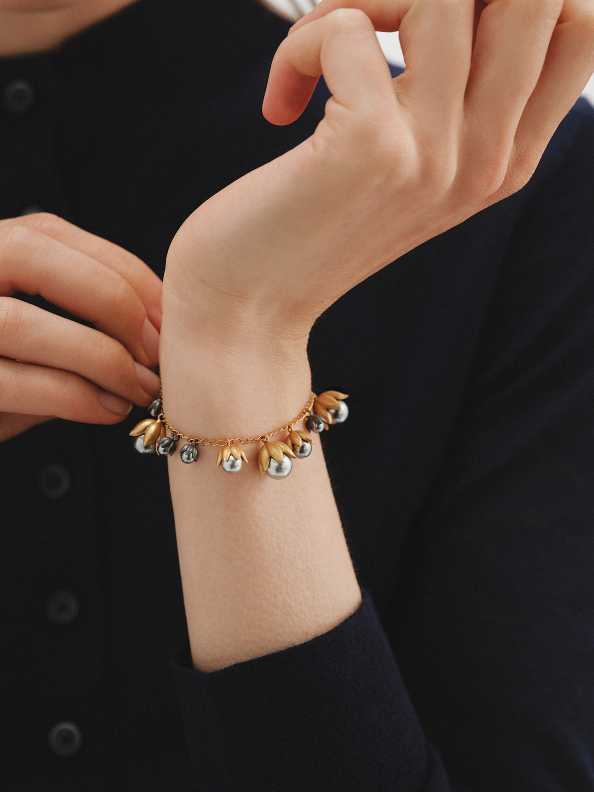 Pulsera bicolor bañada en oro amarillo y acabado gunmetal con perlas grises y motivos florales