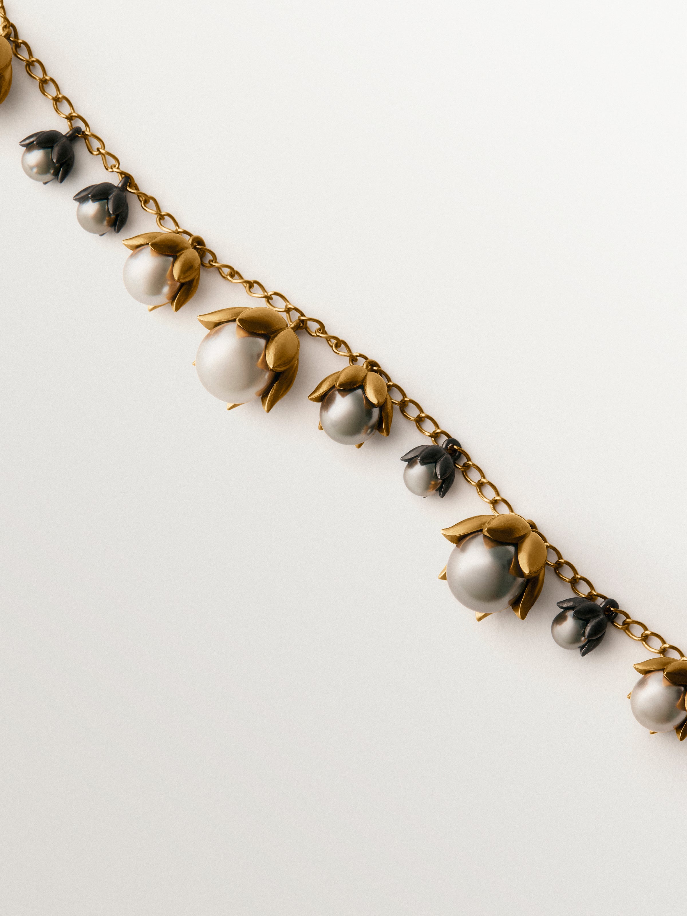 Pulsera bicolor bañada en oro amarillo y acabado gunmetal con perlas grises y motivos florales