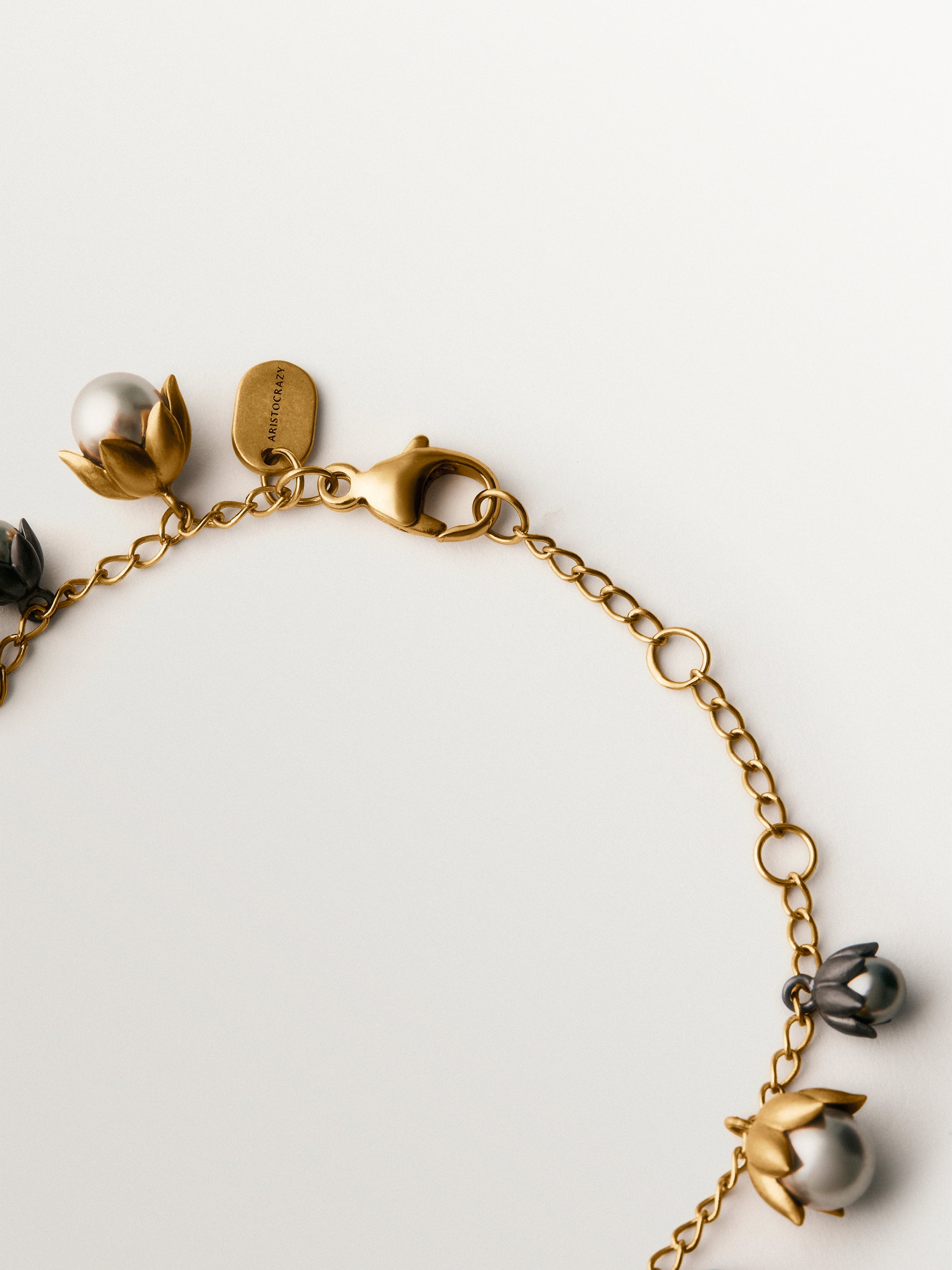 Pulsera bicolor bañada en oro amarillo y acabado gunmetal con perlas grises y motivos florales