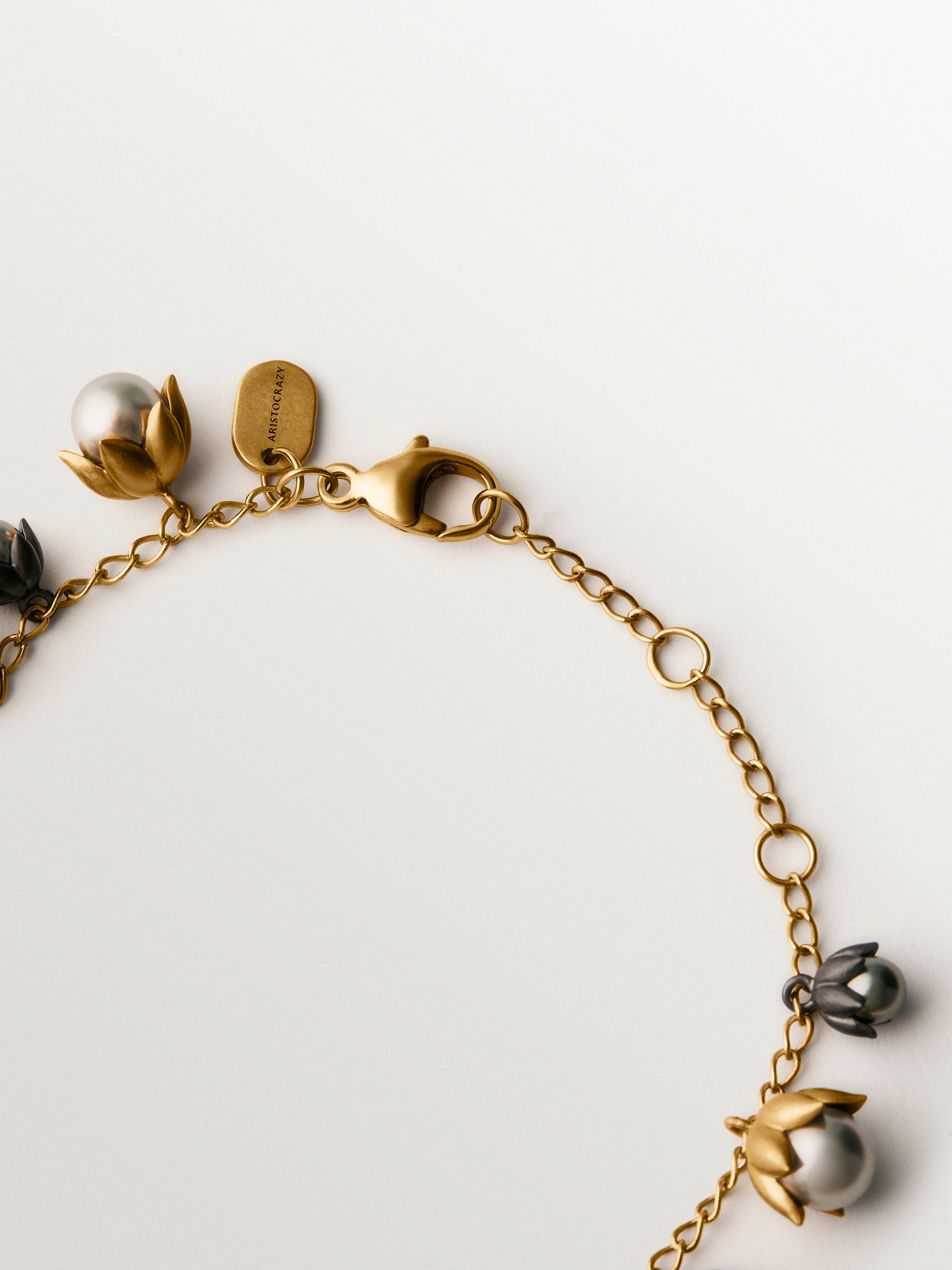 Pulsera bicolor bañada en oro amarillo y acabado gunmetal con perlas grises y motivos florales