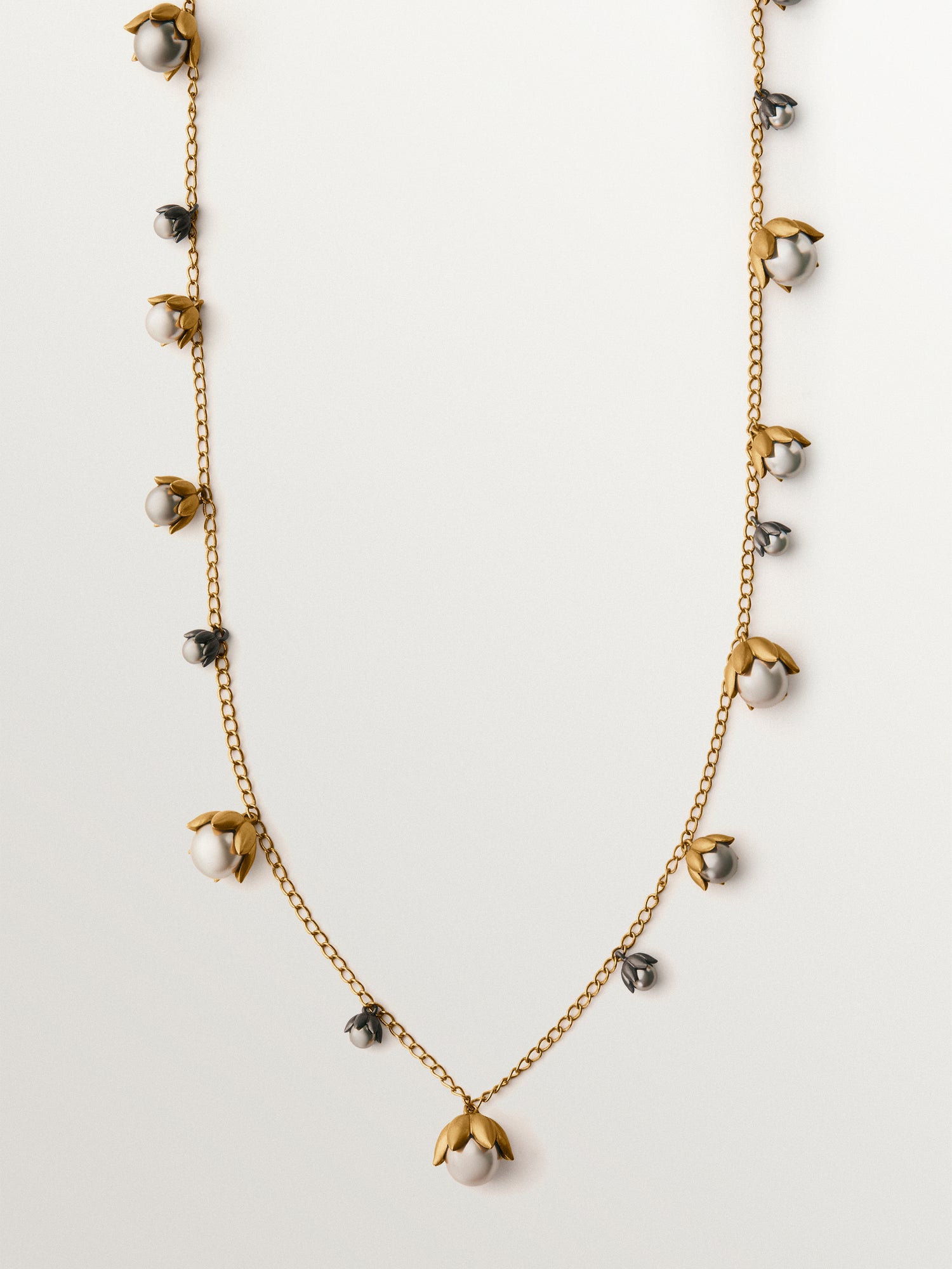 Colgante bicolor bañado en oro amarillo y acabado gunmetal con perlas grises y motivos florales