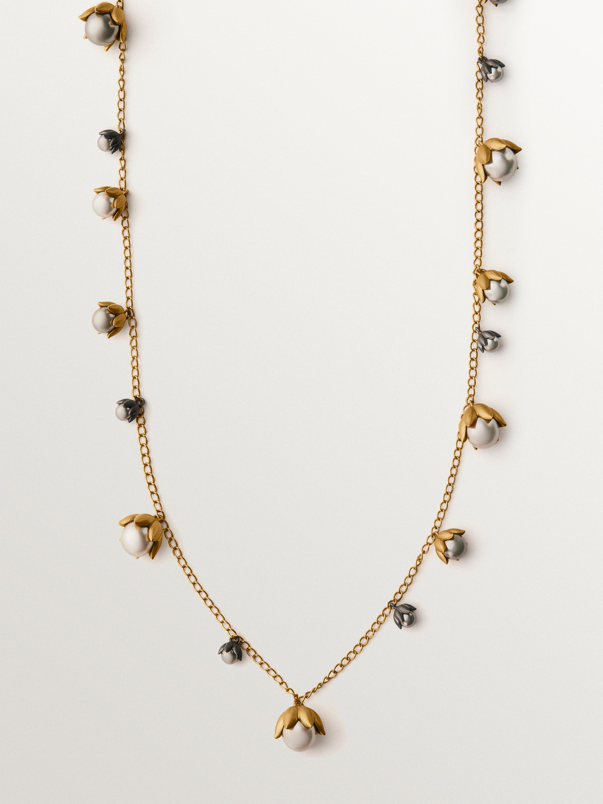 Colgante bicolor bañado en oro amarillo y acabado gunmetal con perlas grises y motivos florales