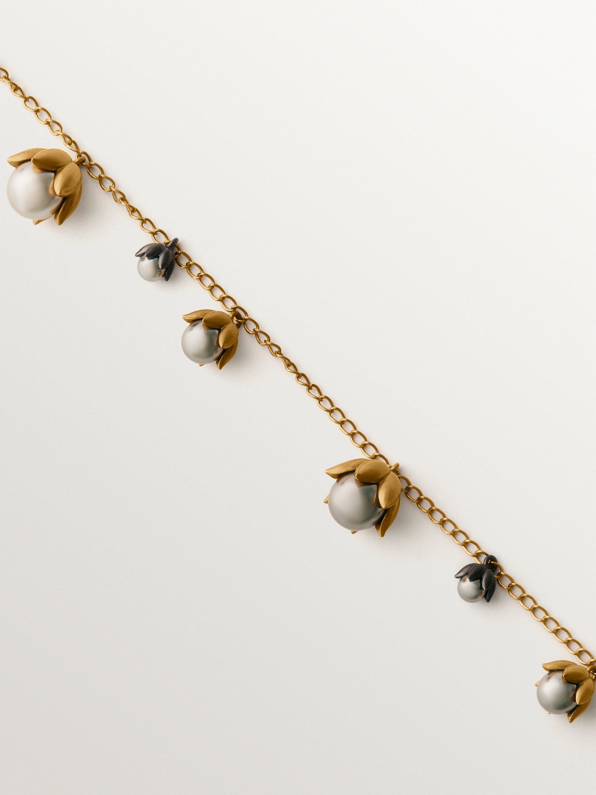 Colgante bicolor bañado en oro amarillo y acabado gunmetal con perlas grises y motivos florales