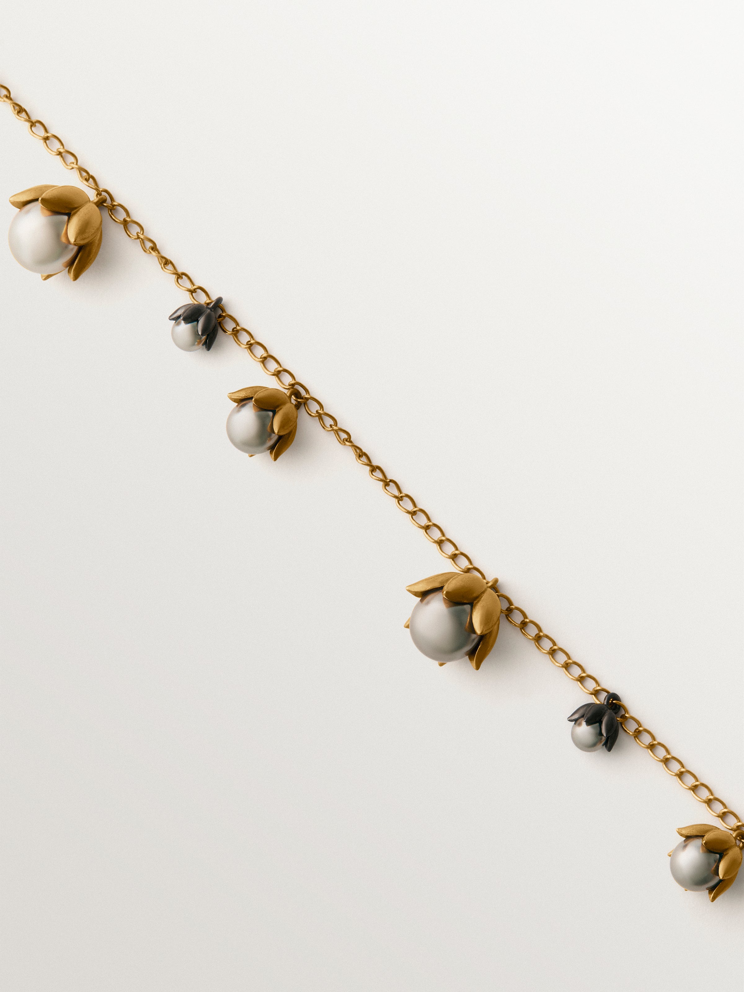 Colgante bicolor bañado en oro amarillo y acabado gunmetal con perlas grises y motivos florales