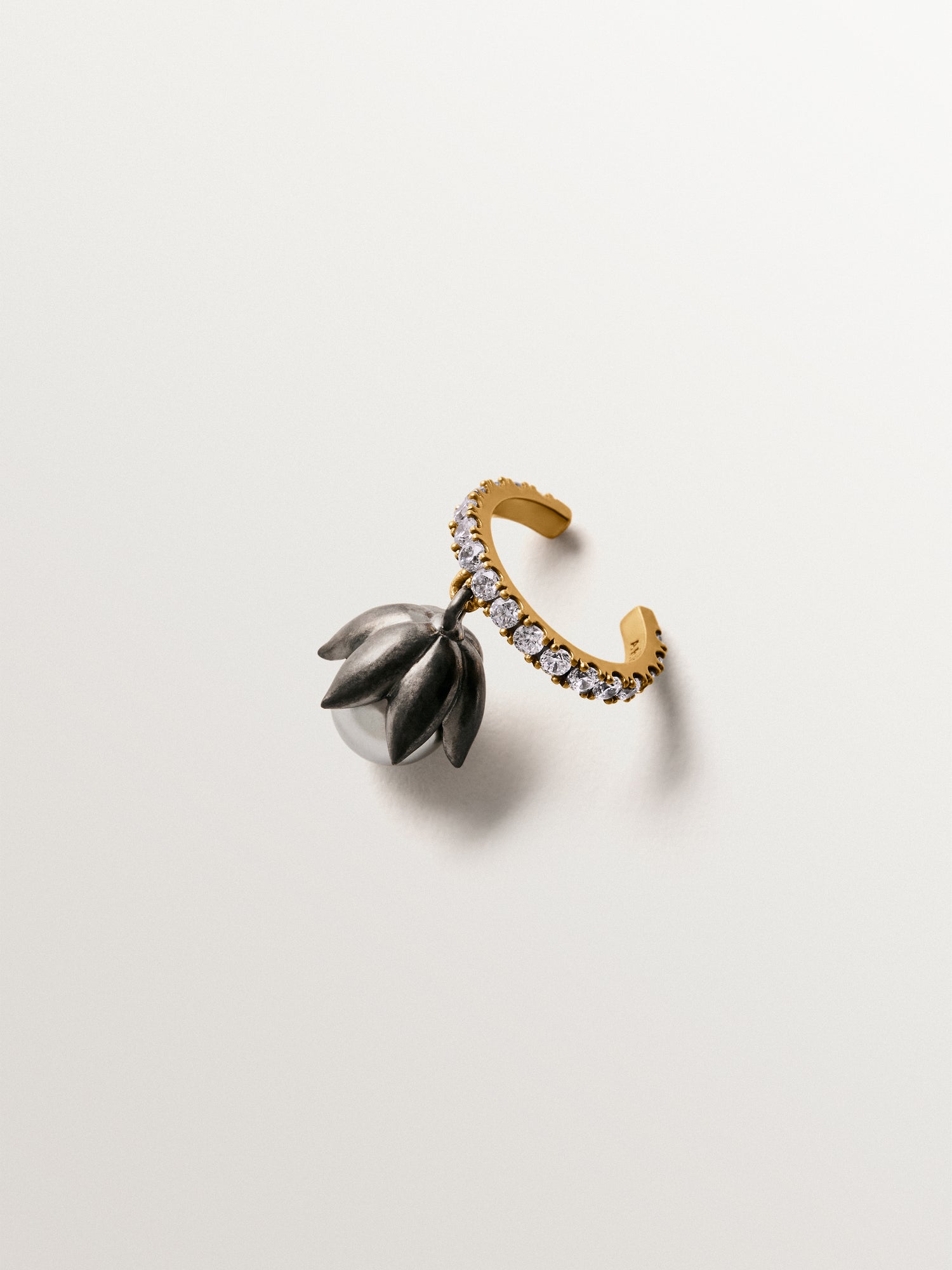Earcuff bicolor bañado en oro amarillo con acabado gunmetal, perlas grises, cristales y forma de flor