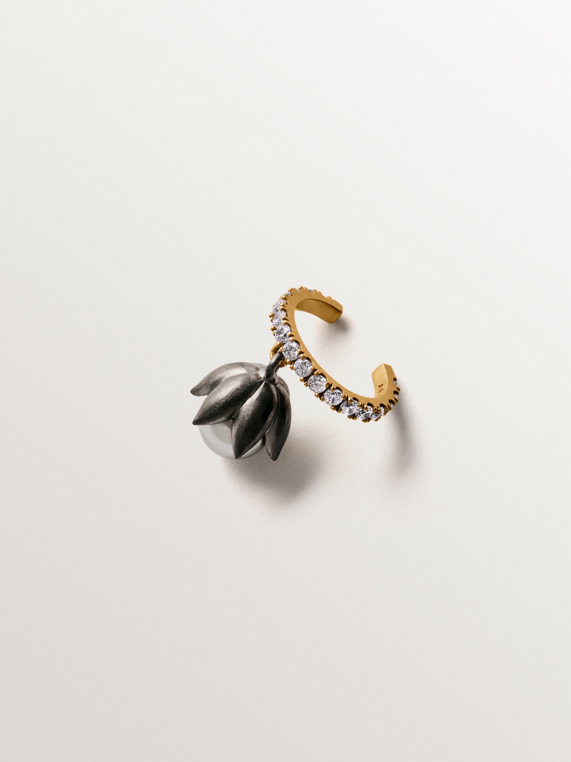 Earcuff bicolor bañado en oro amarillo con acabado gunmetal, perlas grises, cristales y forma de flor