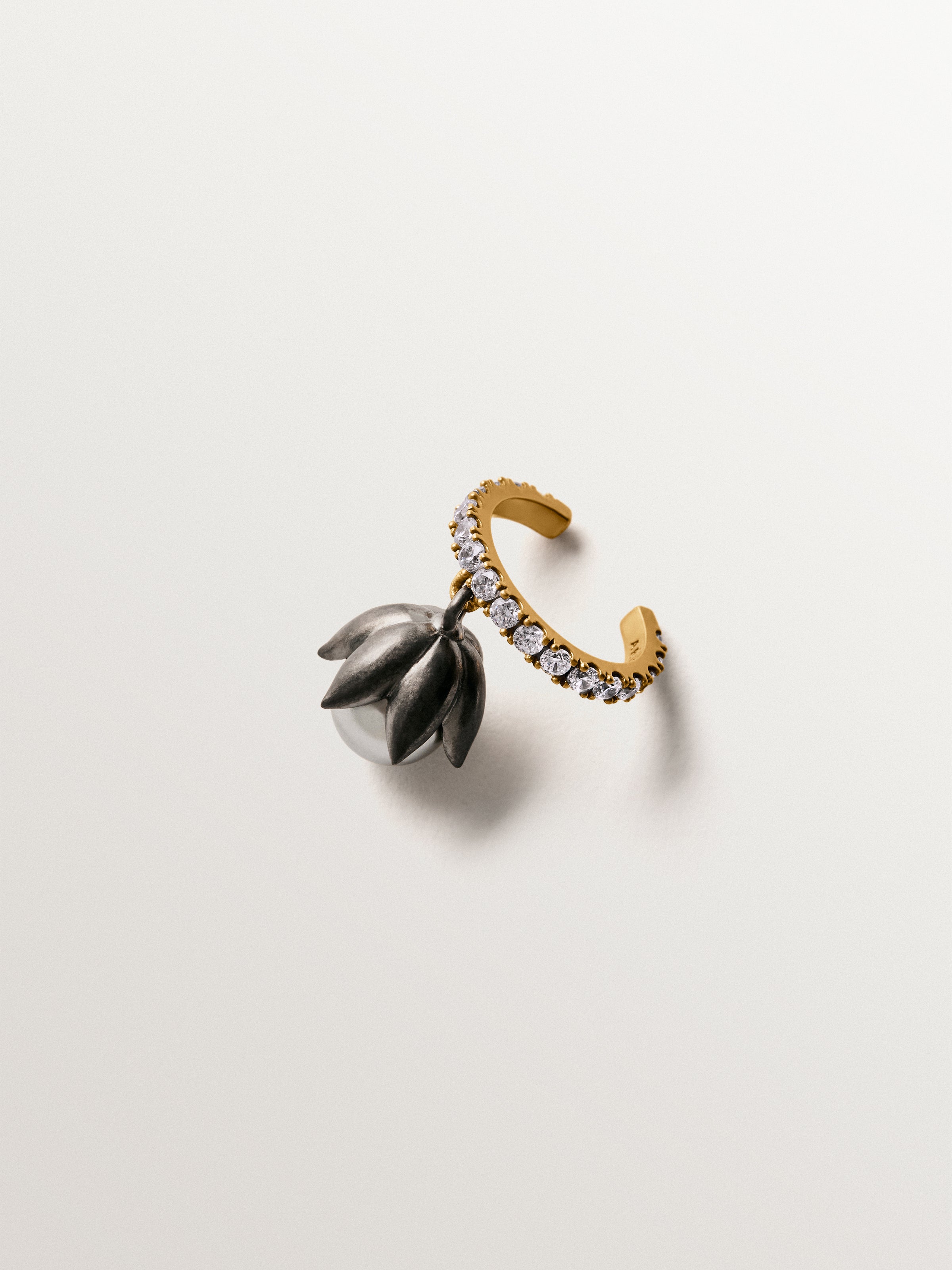 Earcuff bicolor bañado en oro amarillo con acabado gunmetal, perlas grises, cristales y forma de flor