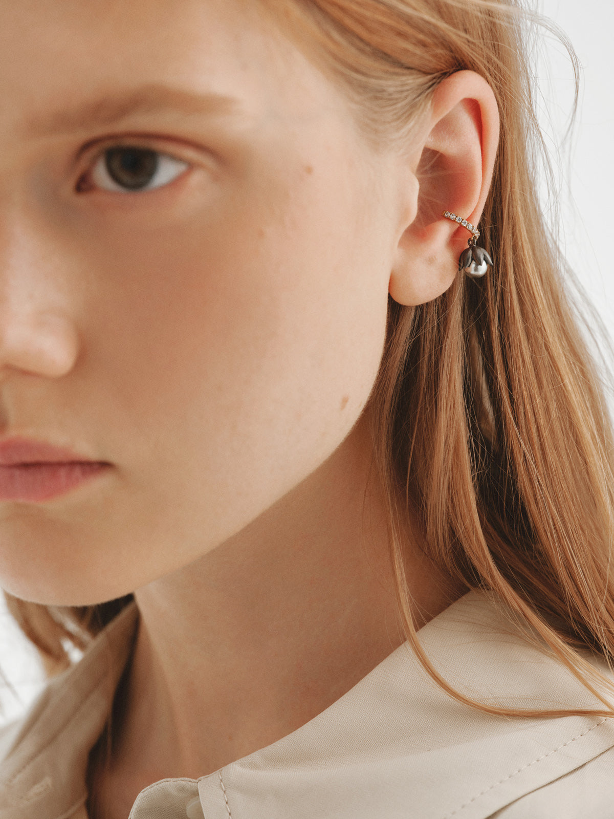 Earcuff bicolor bañado en oro amarillo con acabado gunmetal, perlas grises, cristales y forma de flor