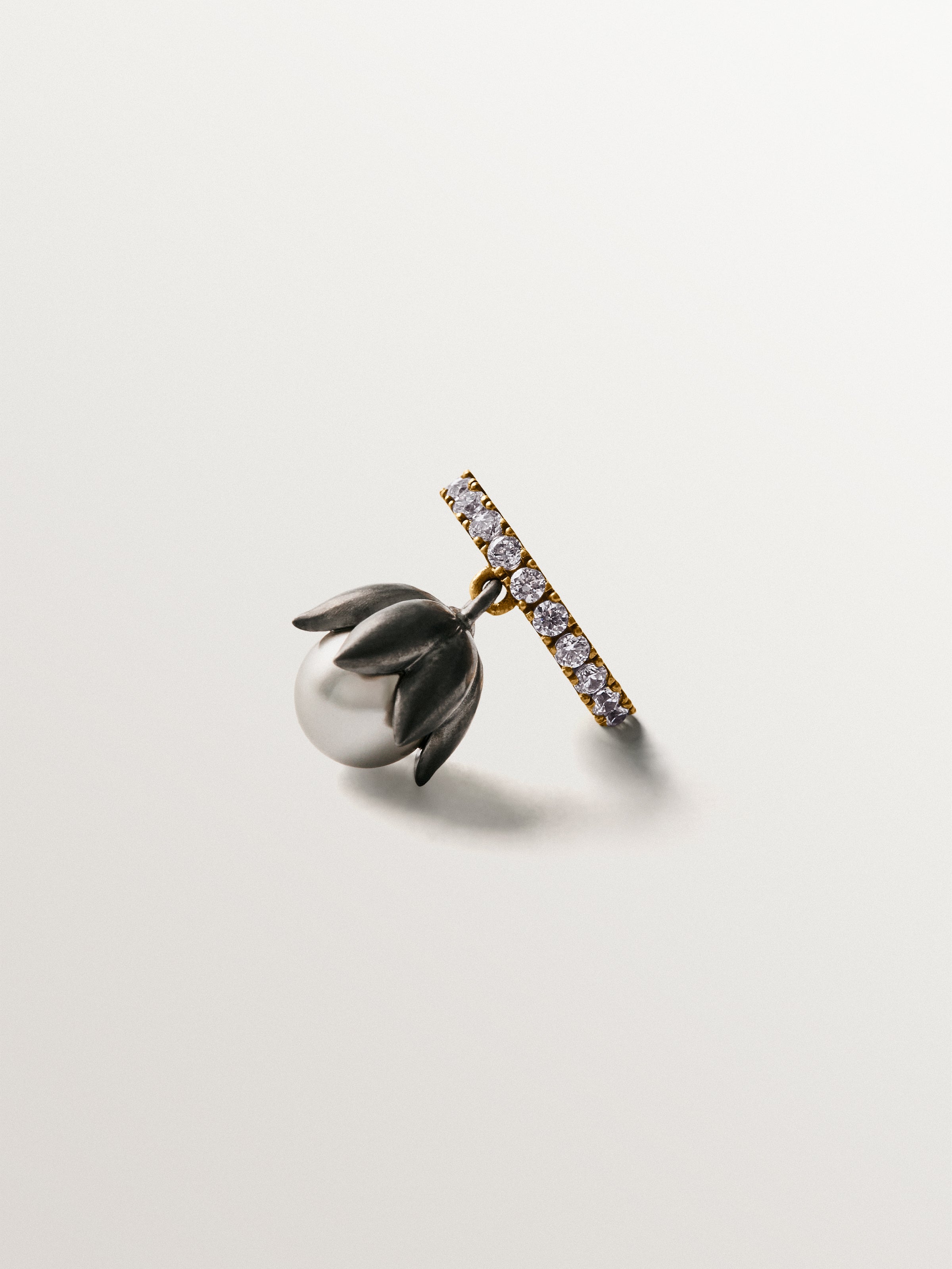 Earcuff bicolor bañado en oro amarillo con acabado gunmetal, perlas grises, cristales y forma de flor