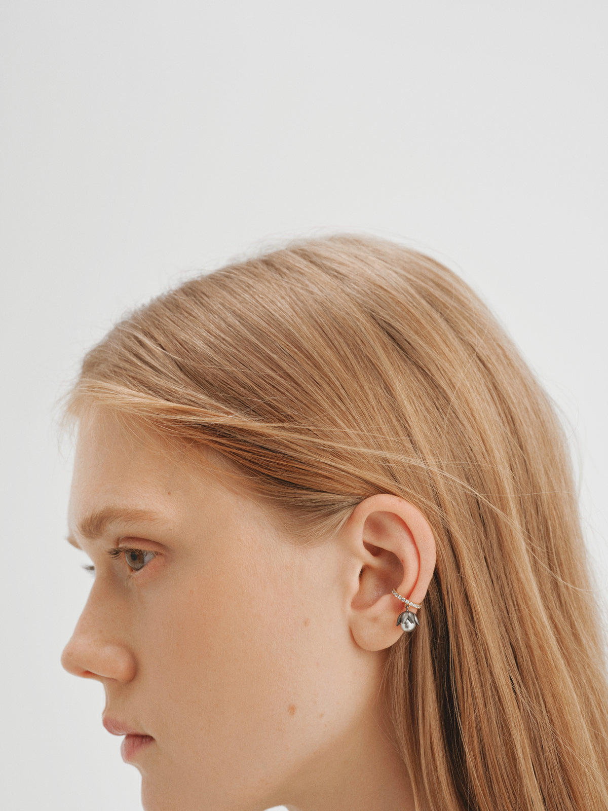 Earcuff bicolor bañado en oro amarillo con acabado gunmetal, perlas grises, cristales y forma de flor